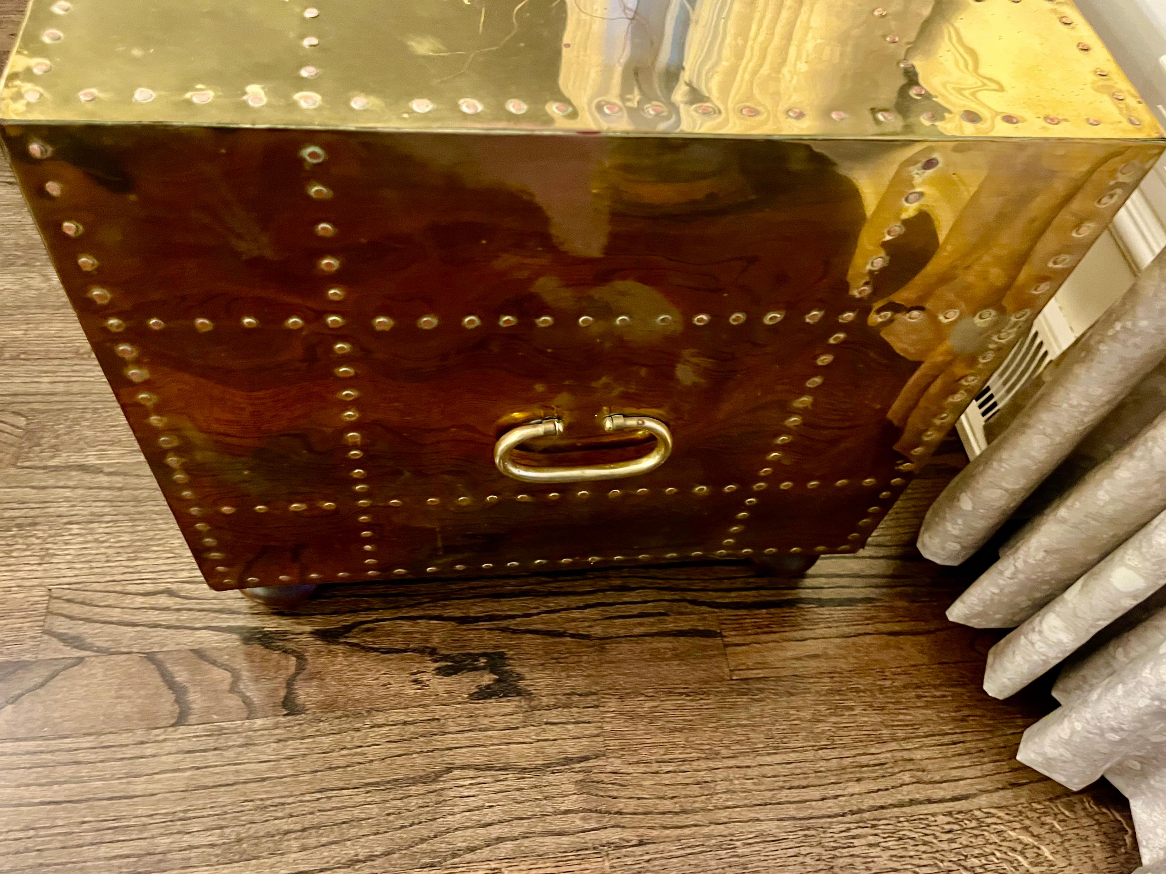 A 1970s brass clad two-drawer chest with nailhead trim and bale handles  on the front and sides all upon squat feet  The back is finished in brass as well. It could function as a side or coffee table.Designed and manufactured by Sarried Ltd from