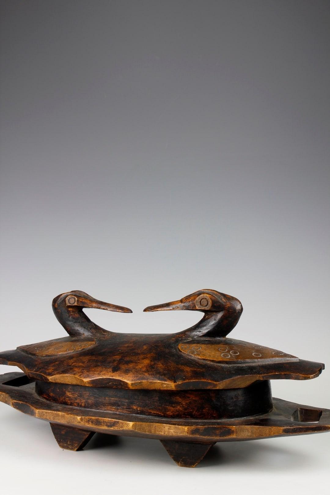 This fine mid-twentieth-century bowl, from the Lozi culture in Zambia, would have been traditionally used to serve and store food. The bowl's base has been made from a single piece of wood, and two beautifully carved ducks decorate the lid.