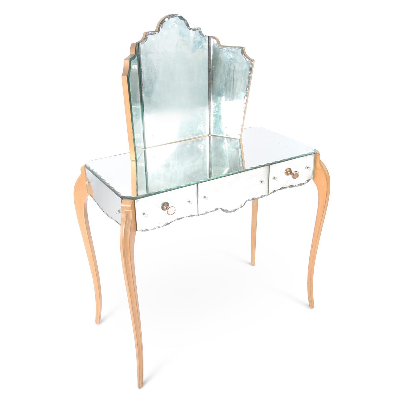 This elegant mirror dressing table, with polished beech legs, original glass, a triptych mirror and copper and glass handles, dates back to mid-20th century, France.