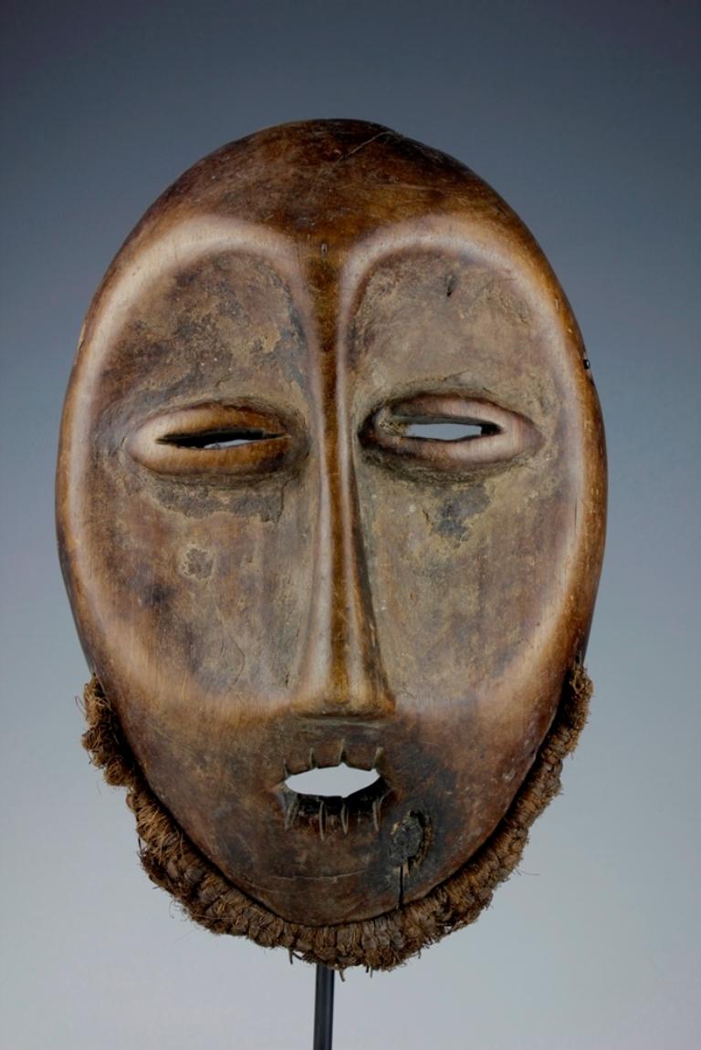 This mid-twentieth century finely carved mask, from the Lega culture in the Democratic Republic of the Congo, displays the typically heart-shaped face of Lega 'Idimu' masks. Traces of old pigmentation are present around the eyes, and the original