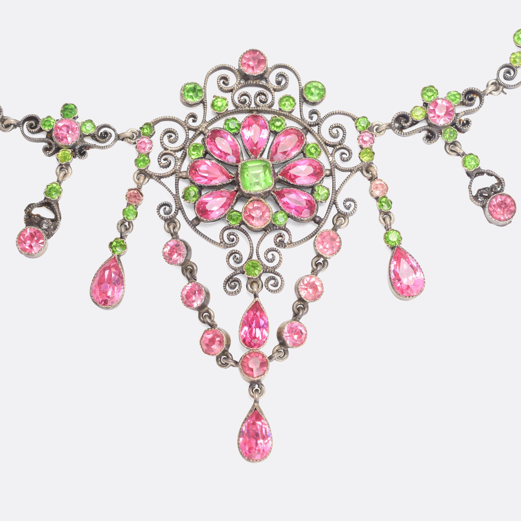 A spectacular mid Victorian Austro-Hungarian necklace and brooch suite set with vibrant green and pink paste stones. It's modelled in Silver, and features beautiful scrolled filigree openwork as well as articulated gemset drops. The stones rest in