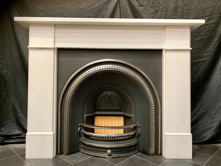 A pleasing mid-Victorian manner statuary marble fireplace surround, a square shelf sits above an unadorned frieze, flanked by wide stepped jambs with splayed separation sections to lower frieze level, all supported on moulded foot blocks. A clean