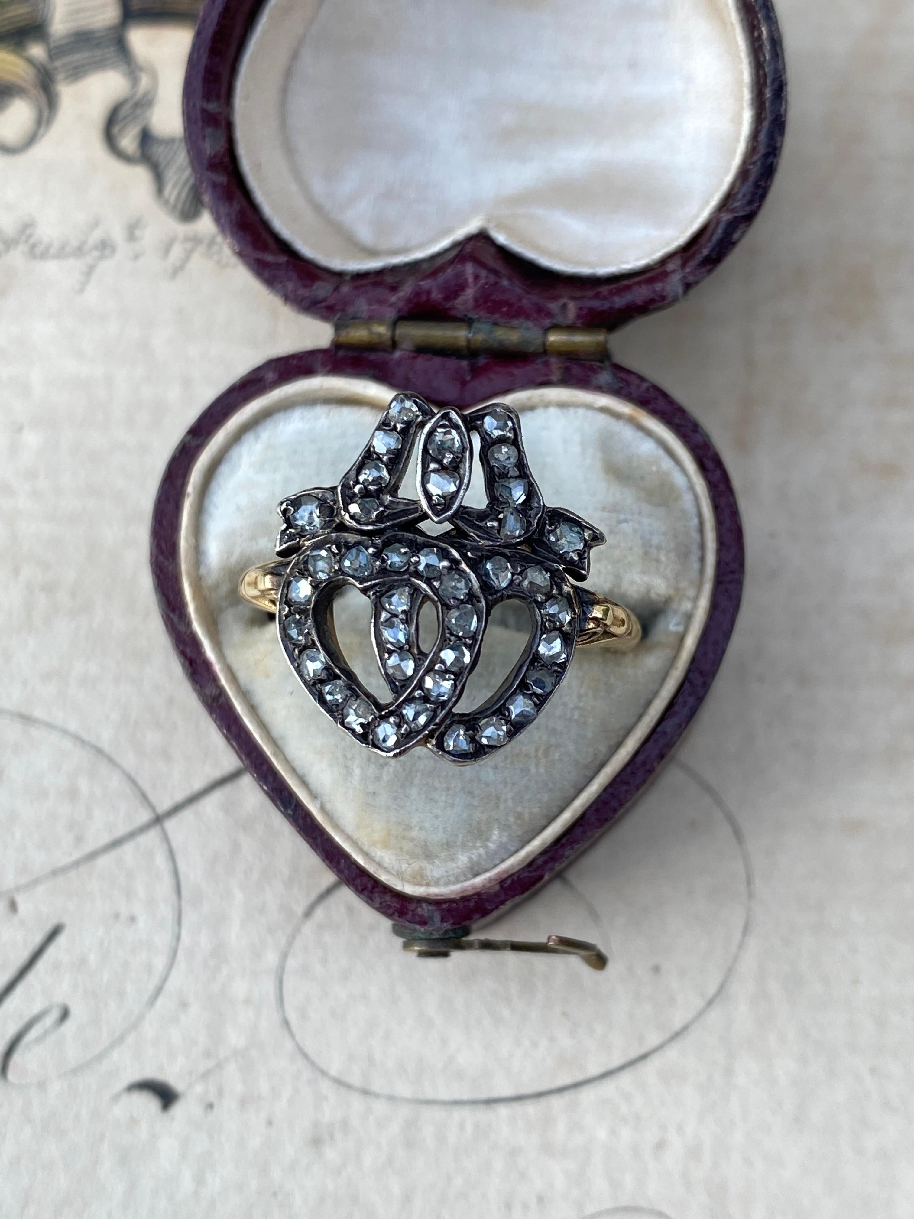 A pair of mid-Victorian diamond lined sweethearts nestled side-by-side and crowned with a twinkling bow. Sweet as can be. Currently a size 6.

Metal: Silver topped 18K

Weight: 3.7 grams

Measurements: 16 mm north to south

Markings: none