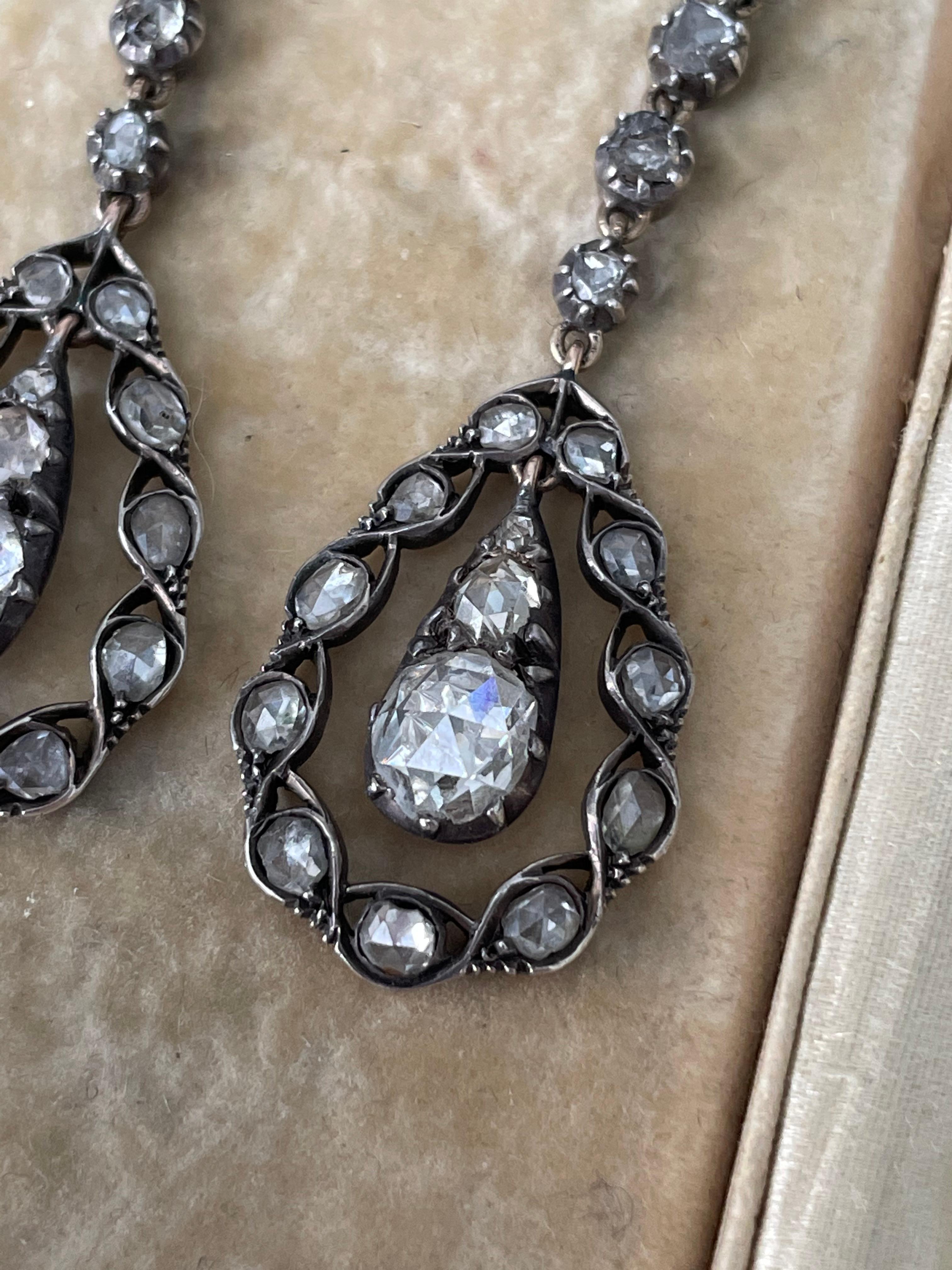 These romantic mid-Victorian diamond pendant earrings are composed of a course of four graduated rose-cut diamonds gracefully dangling a glittering rose-cut diamond frame, suspending a ravishing rose-cut diamond drop. Hand fabricated in darkened
