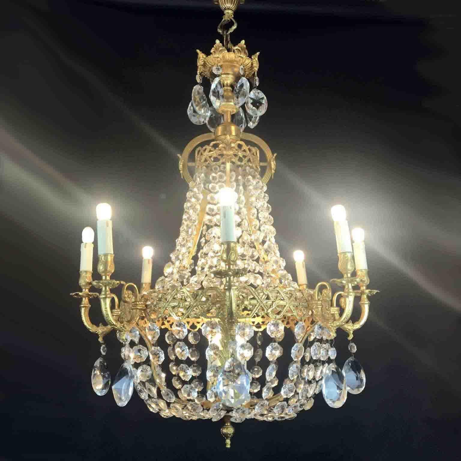 A charming Italian thirteen-light 24-karat gilded cast bronze  chandelier realized around 1970s, richly decorated with crystal festoons and pendants, with a birdcage Empire style frame, eight curved arms ending with Edison 14 candles, additional