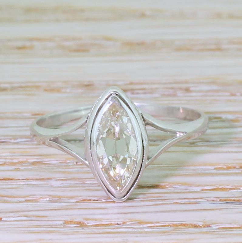 A delightful vintage marquise cut diamond ring. The stunning diamond in the centre displays a soft champagne hue and is absolutely fizzing with fire and brilliance. The stone is rubover set in white gold with engraved detailing in the gallery,