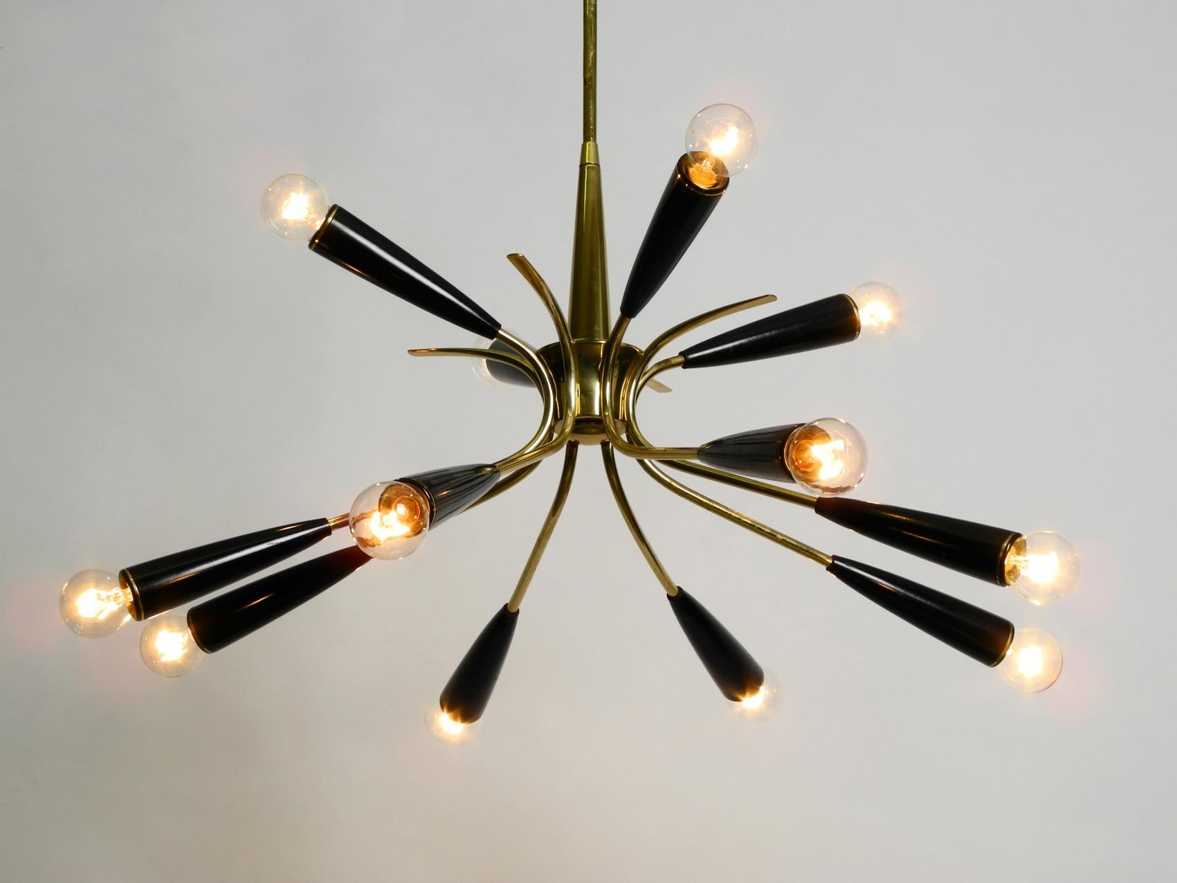 Very rare Mid-Century Modernist Sputnik brass ceiling lamp with cones made of bakalite.
Very nice 1950s Classic. Atomic design in good condition with great patina.
Twelve E14 sockets. Eight arms directed down and four up. Brass frame, bakalite