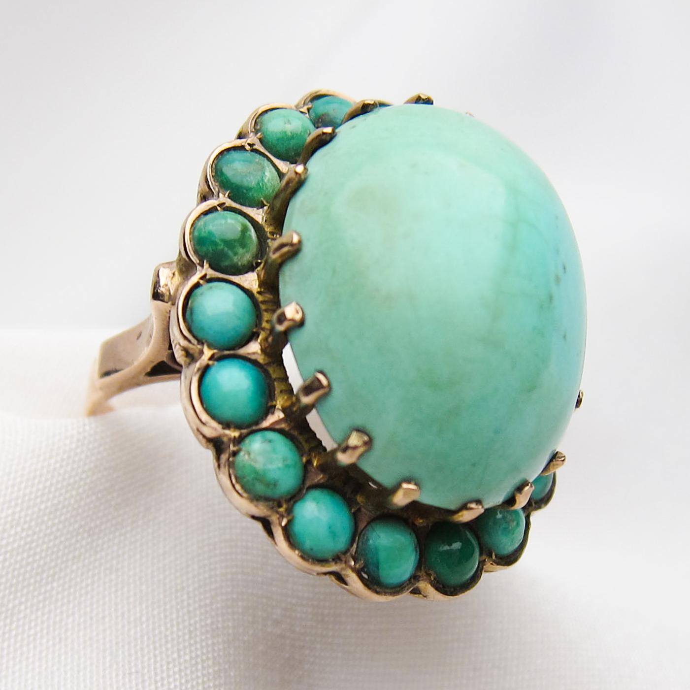This spectacular midcentury turquoise ring is a wonderful find and a true statement piece. The setting is 14KT yellow gold featuring a 26.86 carat cabochon-cut turquoise, surrounded by small cabochon turquoise stones. This is an amazing right-hand