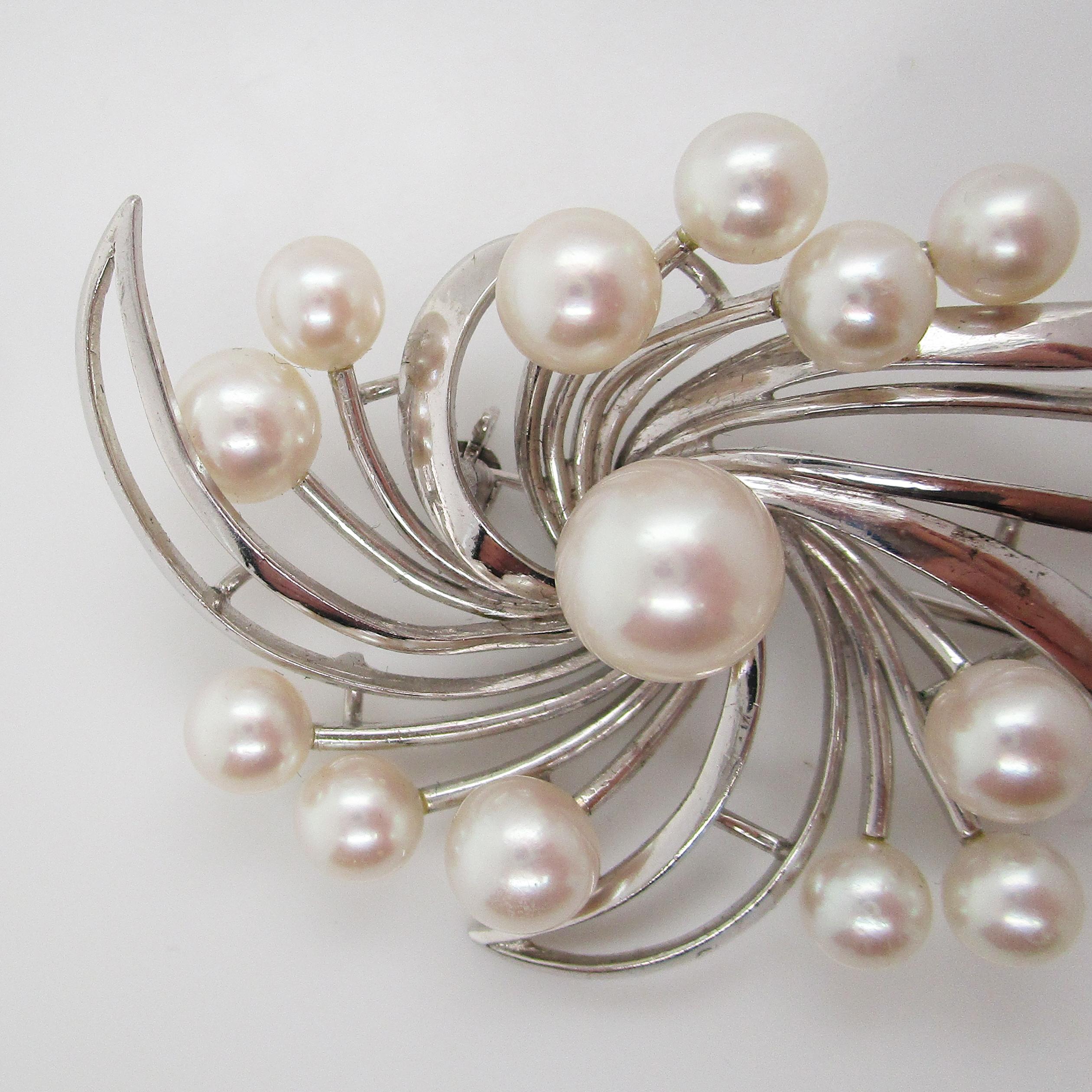 This excellent spray brooch is a lovely mid-century design in 14k white gold with a beautiful array of Mikimoto pearls! The pearls all have an incredible luster and a beautiful white color. The spray design of the brooch is the perfect display for