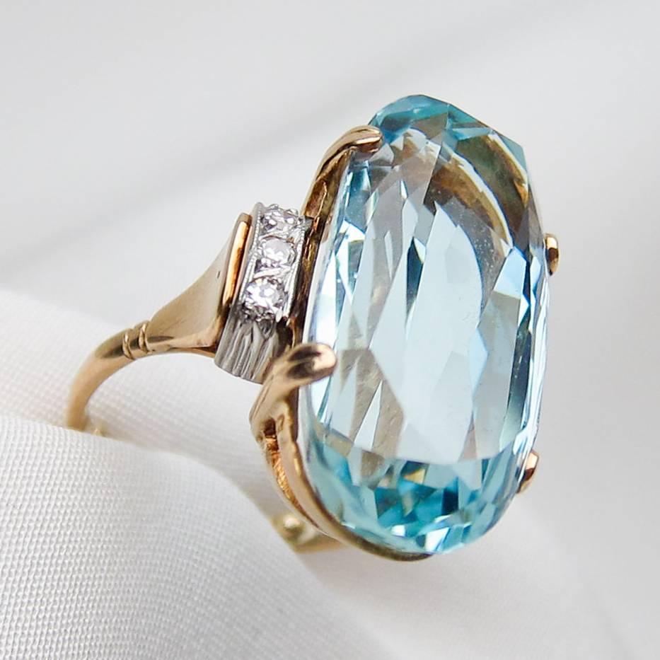 Circa 1950. This made-for-parties midcentury 18KT gold cocktail ring features a 15.30 carat, oval brilliant-cut aquamarine, accented on each side by three single-cut diamonds (six total) set in platinum to enhance sparkle and shine. 
Independently