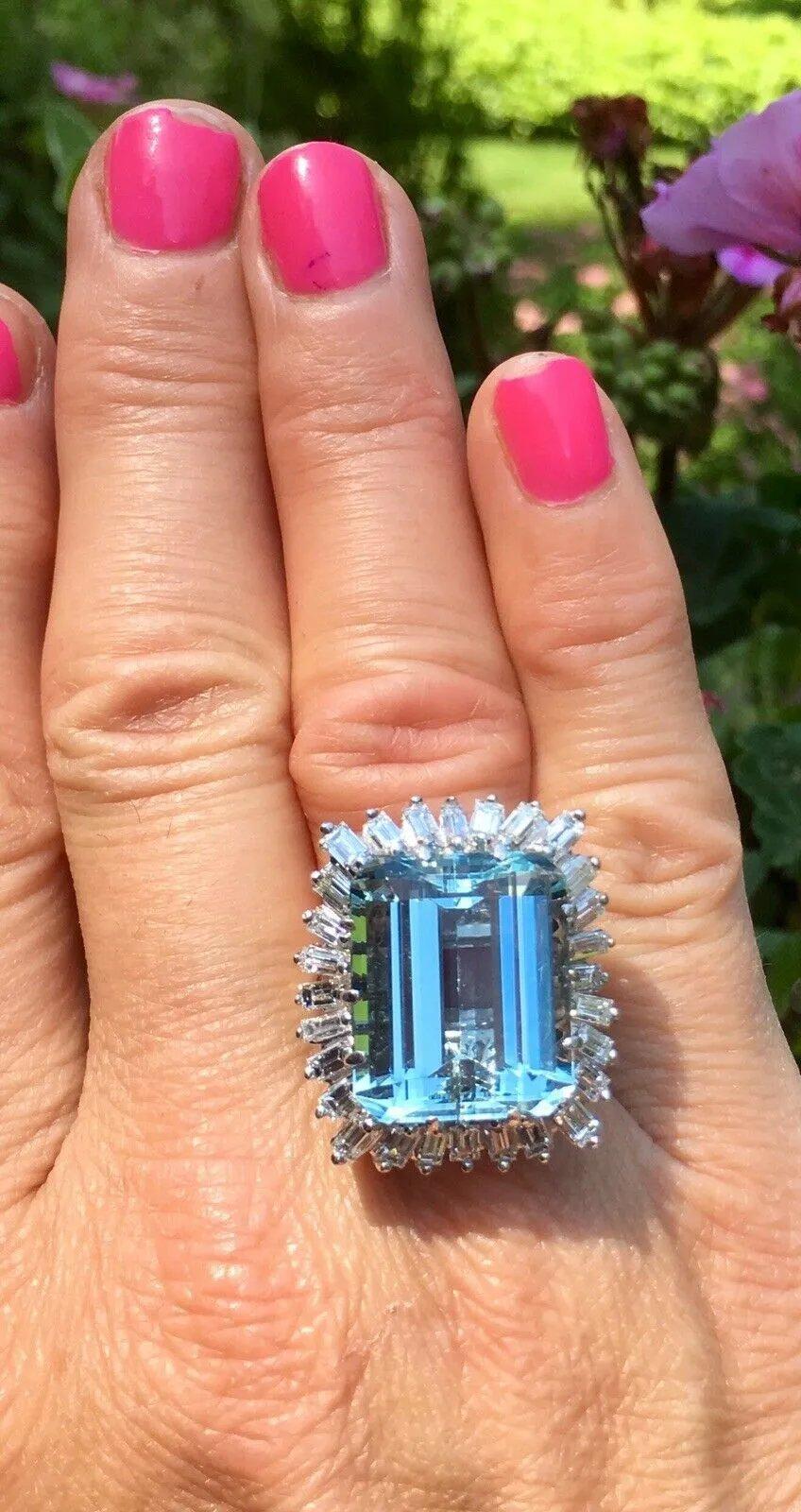 This impressive statement ring features a large emerald cut aquamarine (estimated 16.65 carats set vertically in ten prongs and measures 17.85 x 14.84 x 9.28 mm) with medium to strong blue color and clarity of VVS.

The ring is further surrounded by