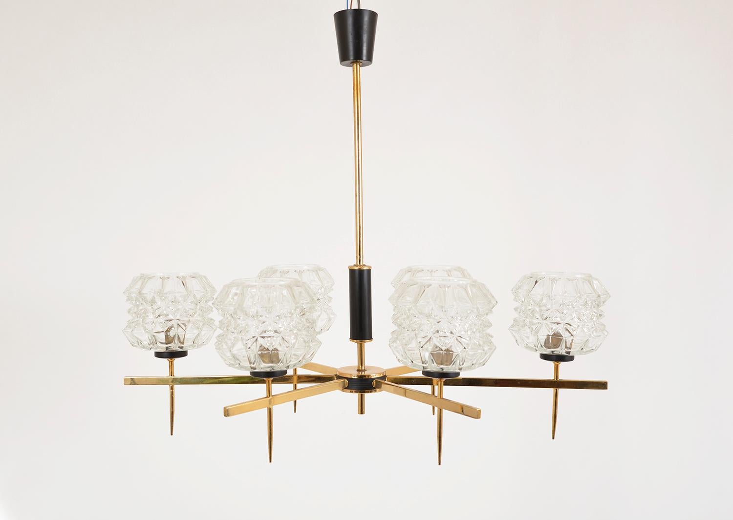 1960s French six-arm pendant chandelier with brass arms, stylish spiked bulb holders and glass lampshades hung from a brass rod with a black plastic ceiling rose. In good working order, however one glass shade has a small hole in it, which doesn’t
