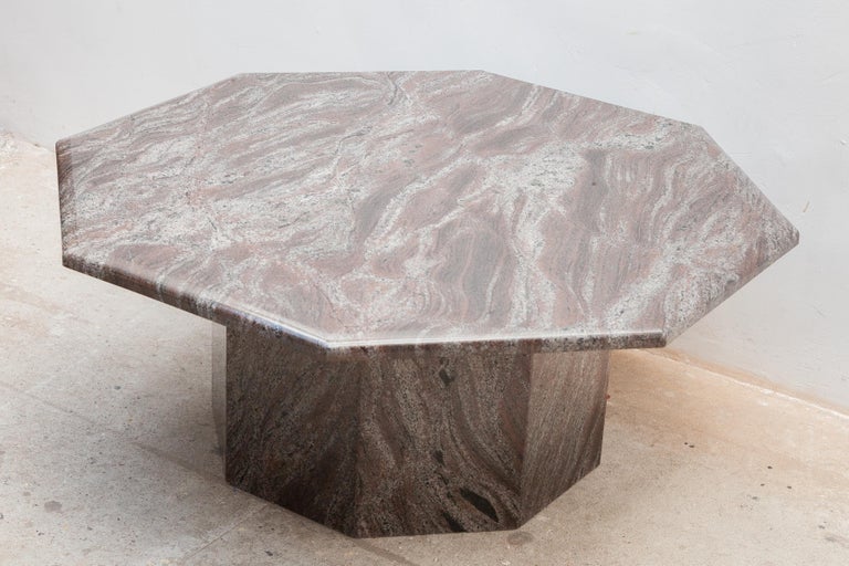 An 1970s Italian coffee table handcrafted out of marble. The fabulous marble features a beautiful wave pattern of different colors in pink, brown, grey and white. The top and base are octagonal designed. 
This vintage marble coffee table will make