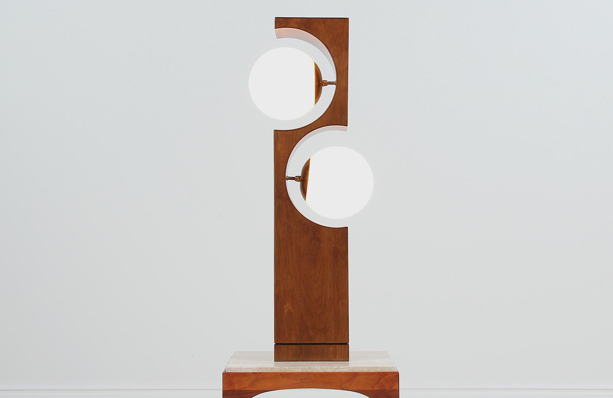 Mid-Century Modern table lamp designed and manufactured by Modeline Lamp Co. of California in the United States, circa 1960s. This sculptural walnut wood design shows bold curves and clean lines on its block base. Two new glass globes are supported