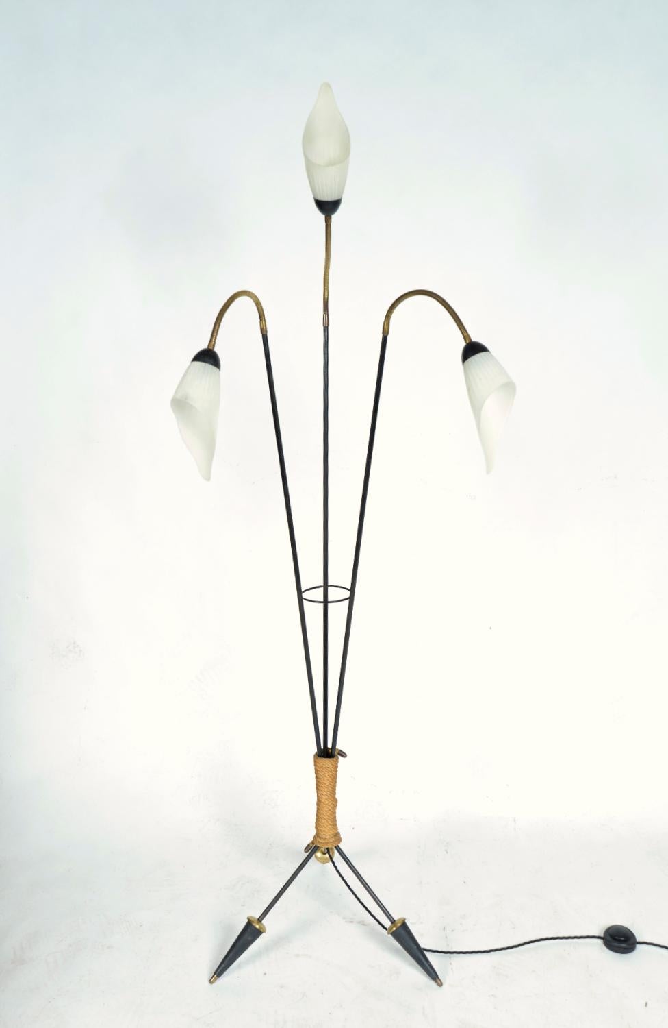 A very stylish Midcentury tripod standard floor lamp dating from the 1950s, with three articulated swan-neck brass arms, with white frosted glass flower shades on black steel rod stems and splayed tripod feet in steel and brass, with a lovely rope