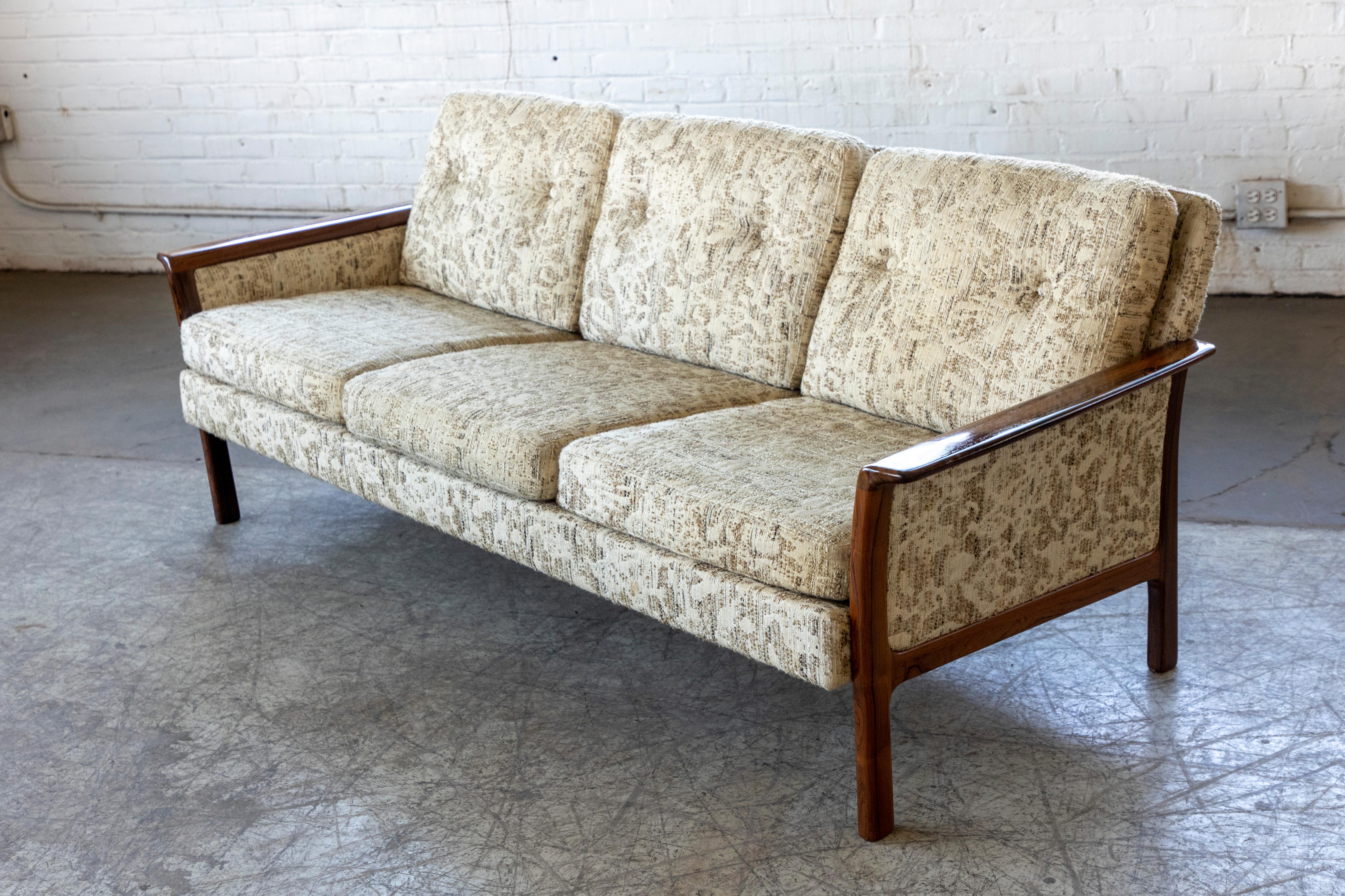 Canapé très élégant et haut de gamme de Hans OIsen conçu pour Vatne Mobler et fabriqué en Norvège dans les années 1960. Canapé en tissu de laine avec cadre et accoudoirs en palissandre. Le bois est en très bon état d'origine avec une couleur et un