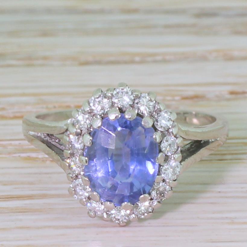 A swoon worthy natural Ceylon sapphire ring. The baby blue sapphire – certified as having had no heat or treatment – is glowingly bright and lively. The stone is claw set within a surround of fourteen high white brilliant cut diamonds within an