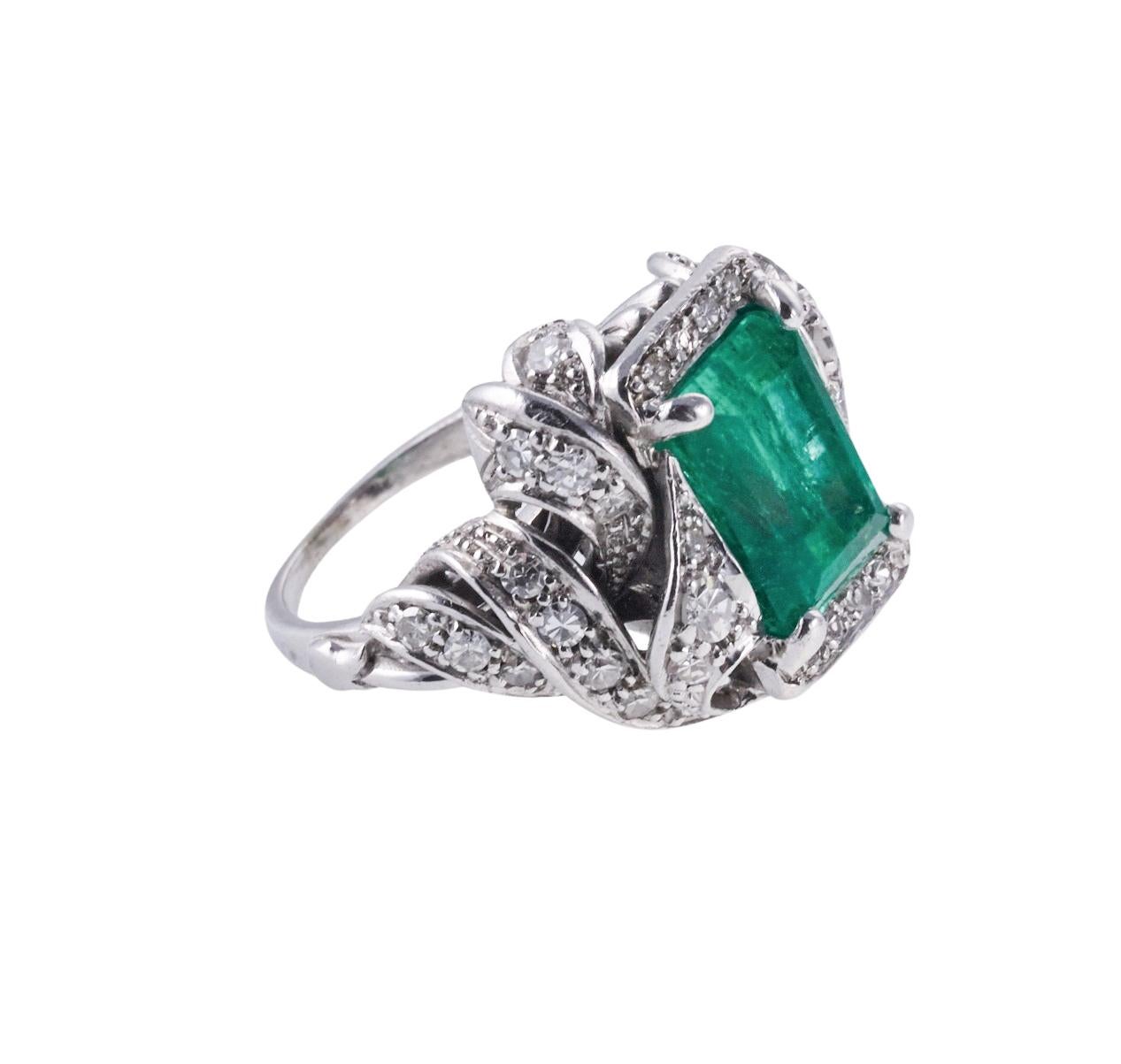 Midcentury 18k white gold cocktail ring, set with center emerald cut emerald - approx. 4.77ct (stone measures 10.9 x 8.1 x 7.8mm), surrounded with approx. 0.90ctw SI/H-I diamonds. Ring size 5, top of the ring measures 20mm x 21mm. Marked k18. Weight
