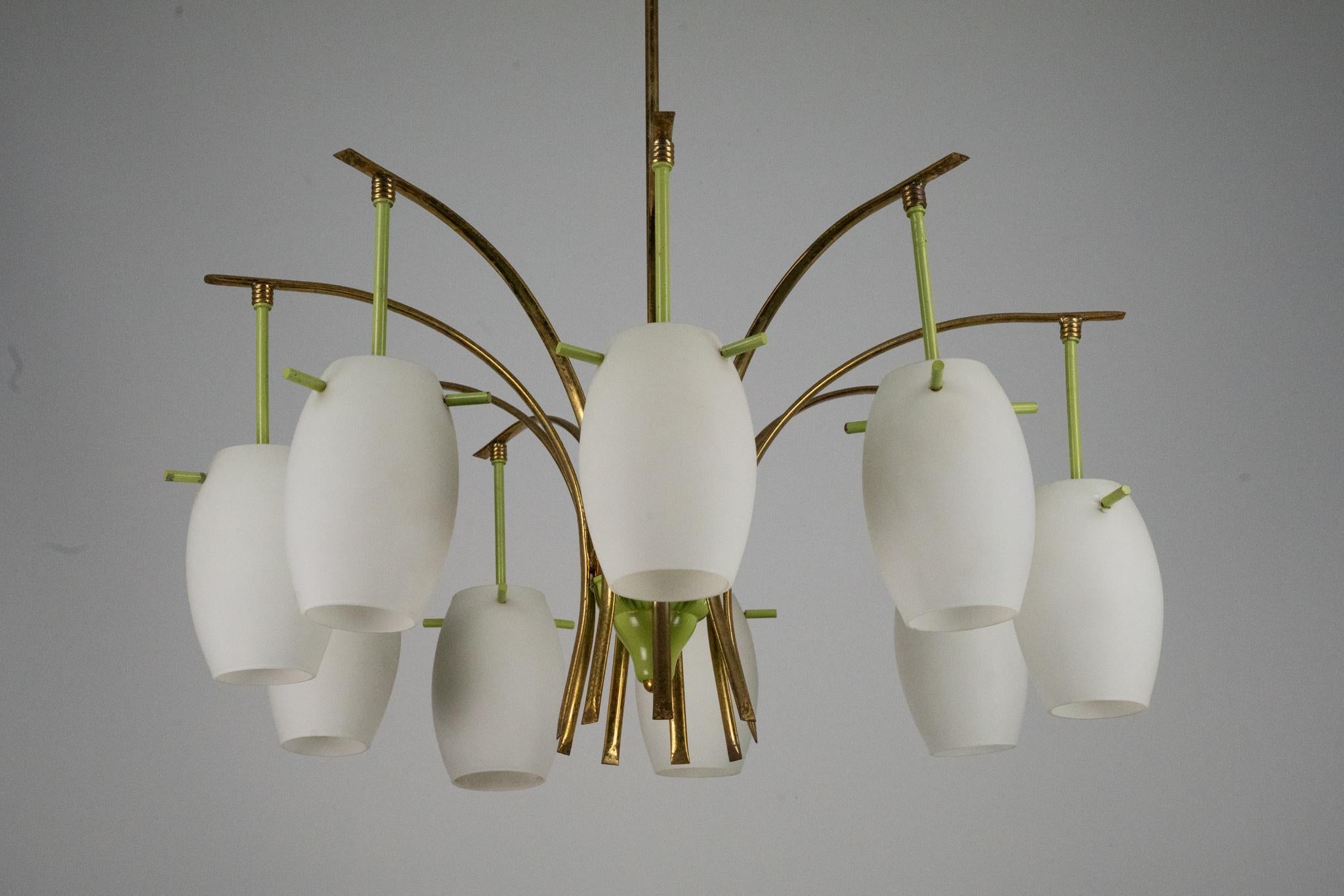 Elegante lampadario di grandi dimensioni della metà del secolo scorso con nove bracci in ottone, finitura laccata verde e paralumi in vetro opalino. Presenta segni dell'età: l'ottone presenta una leggera ossidazione, alcune perdite di lacca e