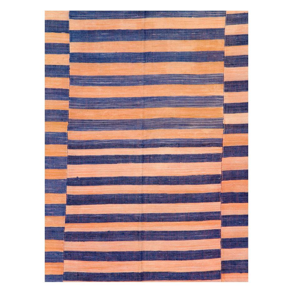 Un tapis Kilim turc vintage à tissage plat, fabriqué à la main au milieu du 20e siècle. 3 sections décalées avec des couleurs variées de kaki, orange, corail et bleu foncé sont attachées ensemble pour créer ce tapis à tissage plat. Les rayures de