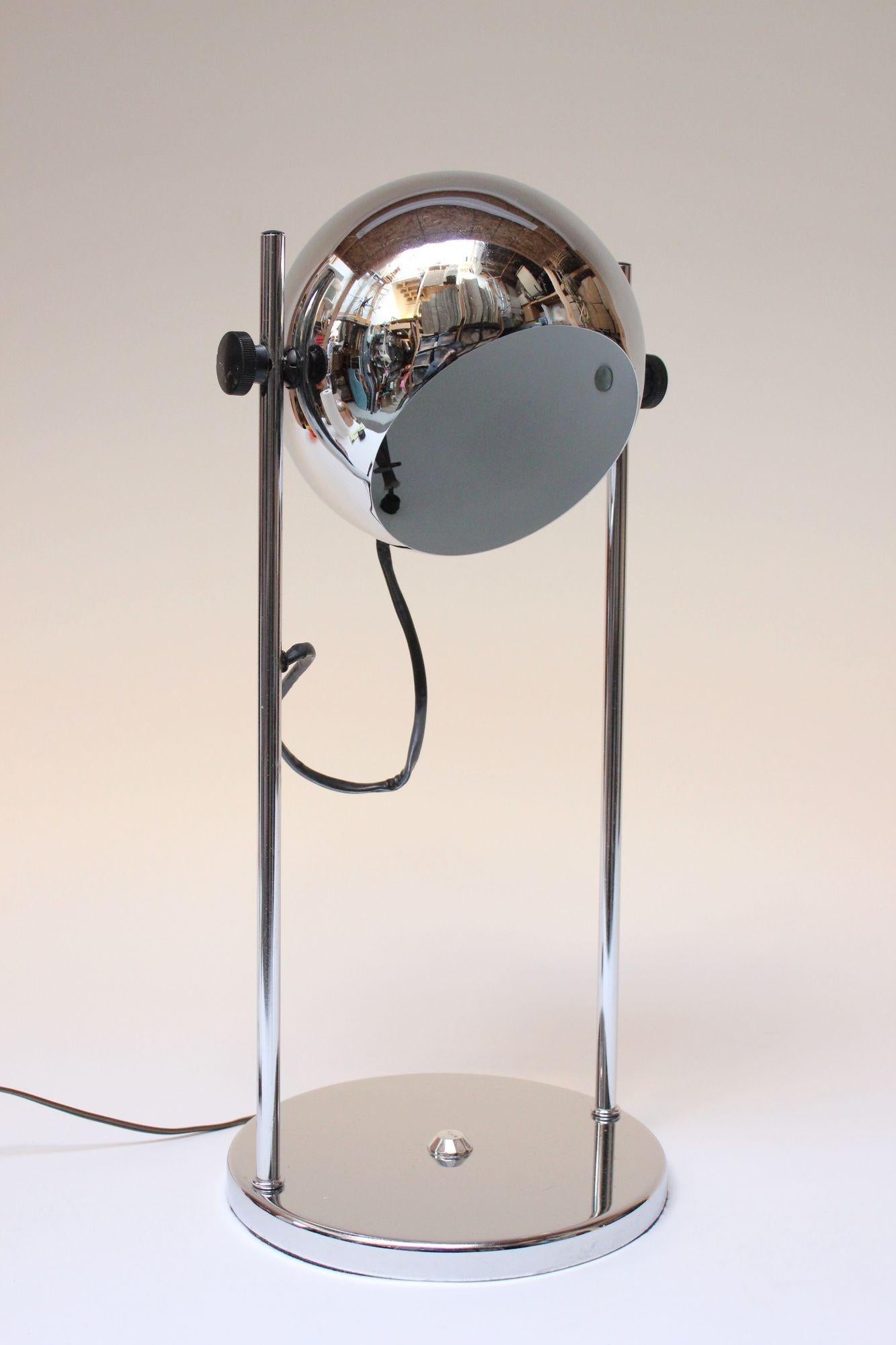Chrome eyeball fixture supported by tubular chrome posts affixed to a round base in the style of Robert Sonneman (ca. 1970s, USA). Fixture pivots in an upward and downward motion (height is fixed, and shade cannot move up and down the pillars, as