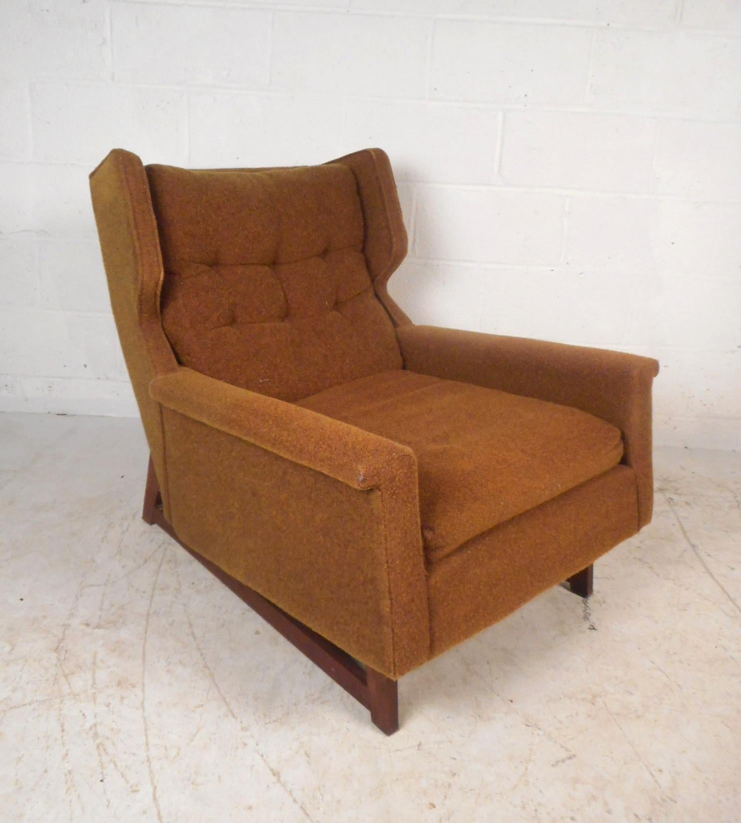 This beautiful vintage modern lounge chair features walnut sled legs, a winged back rest, and plush tufted upholstery. The sleek design sits on an angle ensuring maximum comfort in any seating arrangement. An original orange fabric with tufts cover