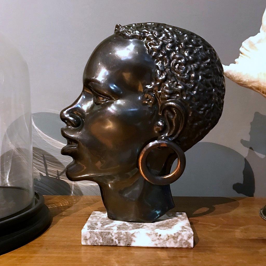 Beautiful Mid-Century modernist bronze head of an African woman made in Austria in the 1950s with a brass earring and a marble base in the style of Hagenauer Werkstatte. 
In very good condition with nice patina.
 