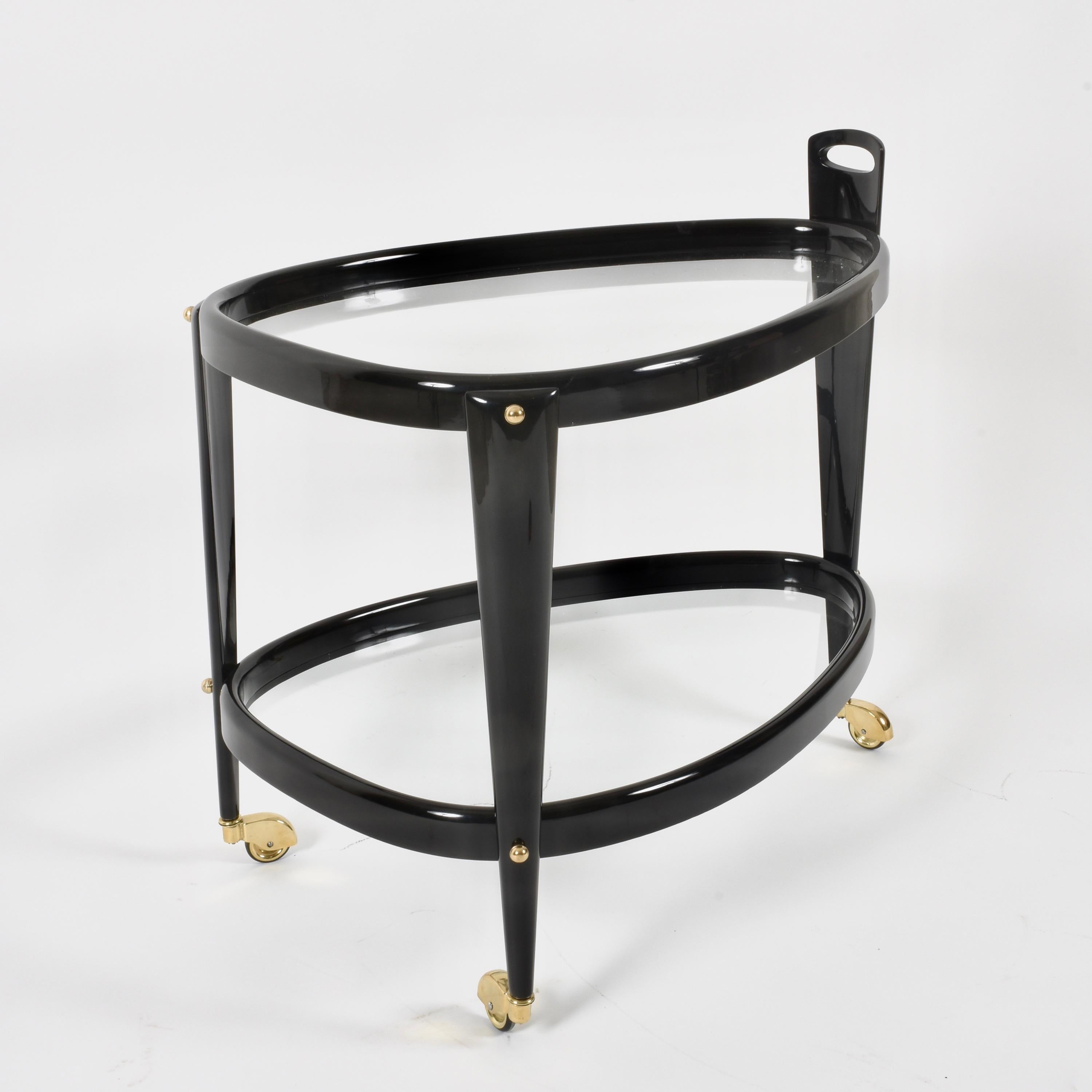 Rare three-wheeled midcentury brass and ebonized wood oval bar cart. It was designed by Aldo Tura during 1950s in Italy.

The never ending elegance of this item issue to the round and soft lines, made unique by the ebonized birch wood and the