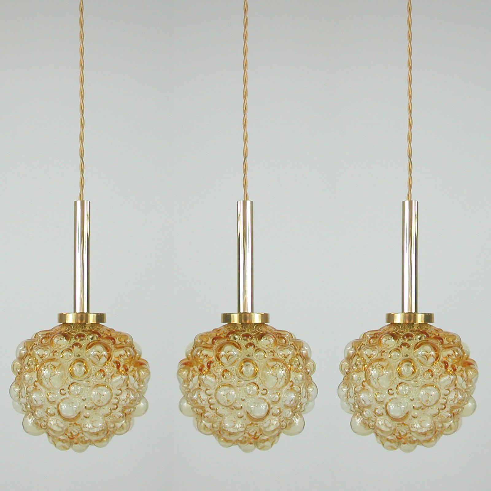 This Space Age pendant light was designed and manufactured in Germany in the 1960s. It features an amber bubble glass lampshade and has got a brass cylinder. The lamp is sold without canopy.

The light has been rewired with new amber / gold