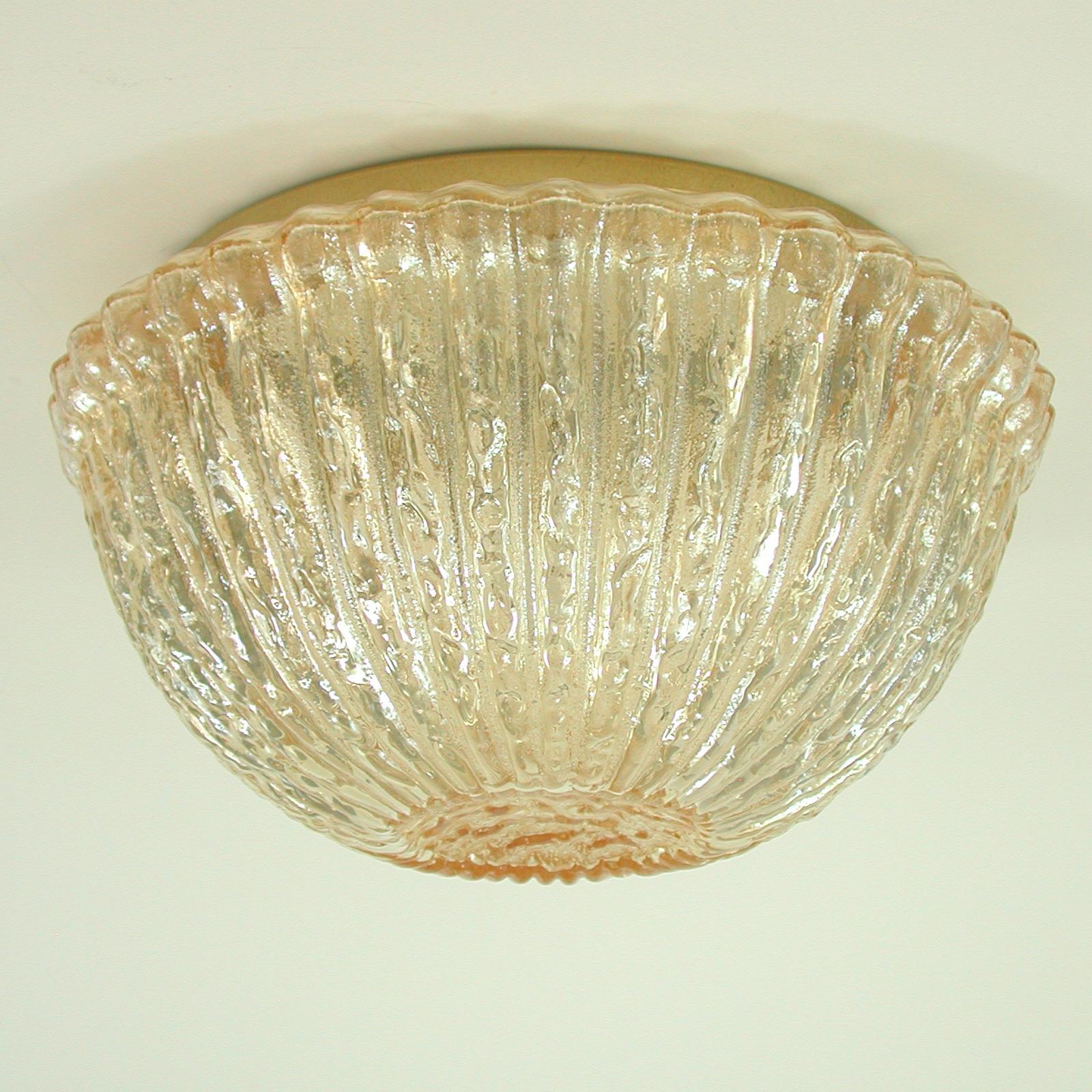 This beautiful 1960s Midcentury flush mount was designed and manufactured in Germany by Glashuette Limburg (model no. A665). It features a thick amber colored textured Murano glass lamp shade and gilt colored mounting. 

The light requires one E27