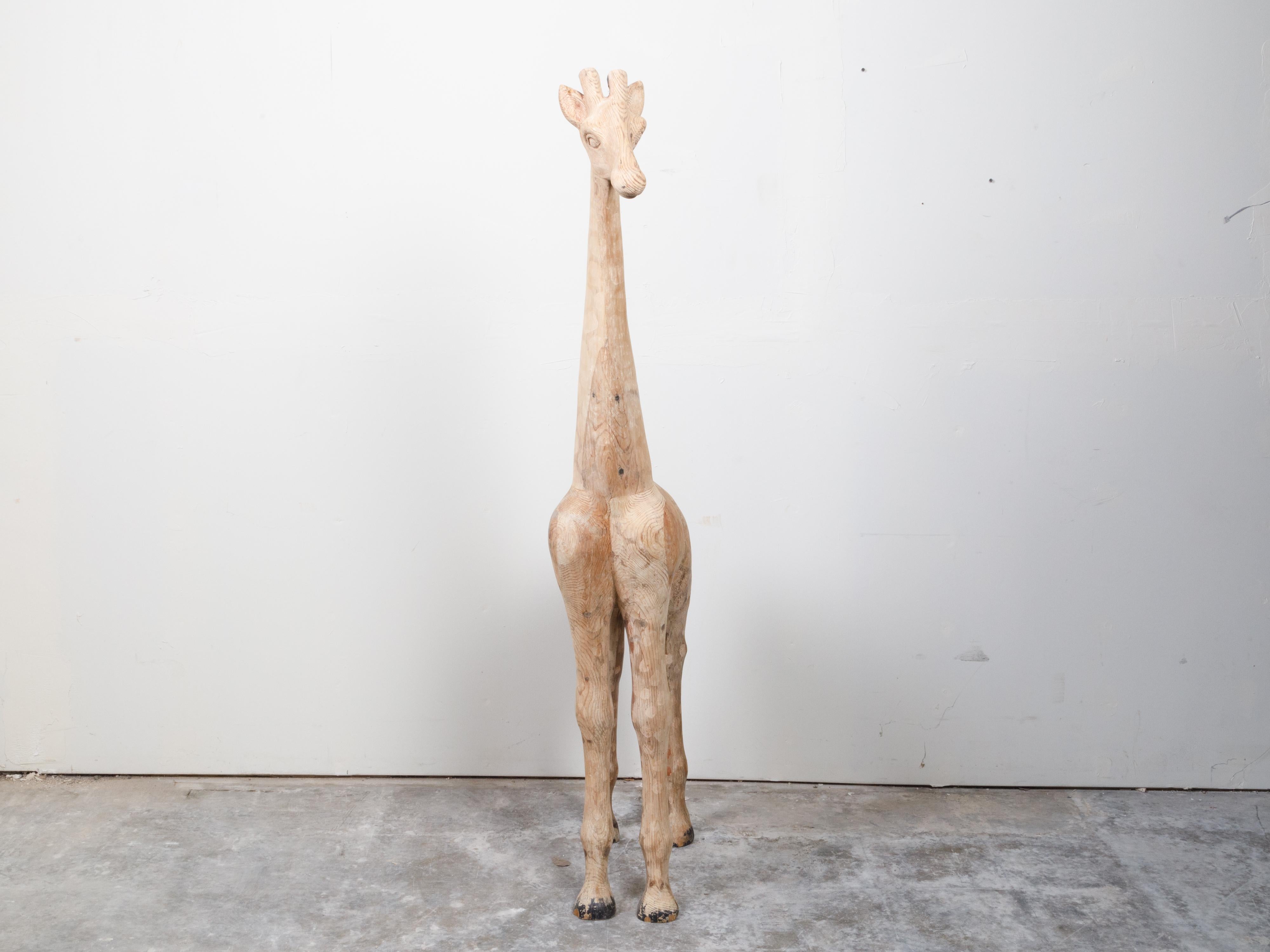 Eine alte amerikanische geschnitzte Giraffenskulptur aus Holz aus der Mitte des 20. Jahrhunderts, mit Flecken. Diese um die Jahrhundertmitte in den USA hergestellte Holzskulptur besticht durch die schöne Darstellung einer Giraffe, die fest auf ihren