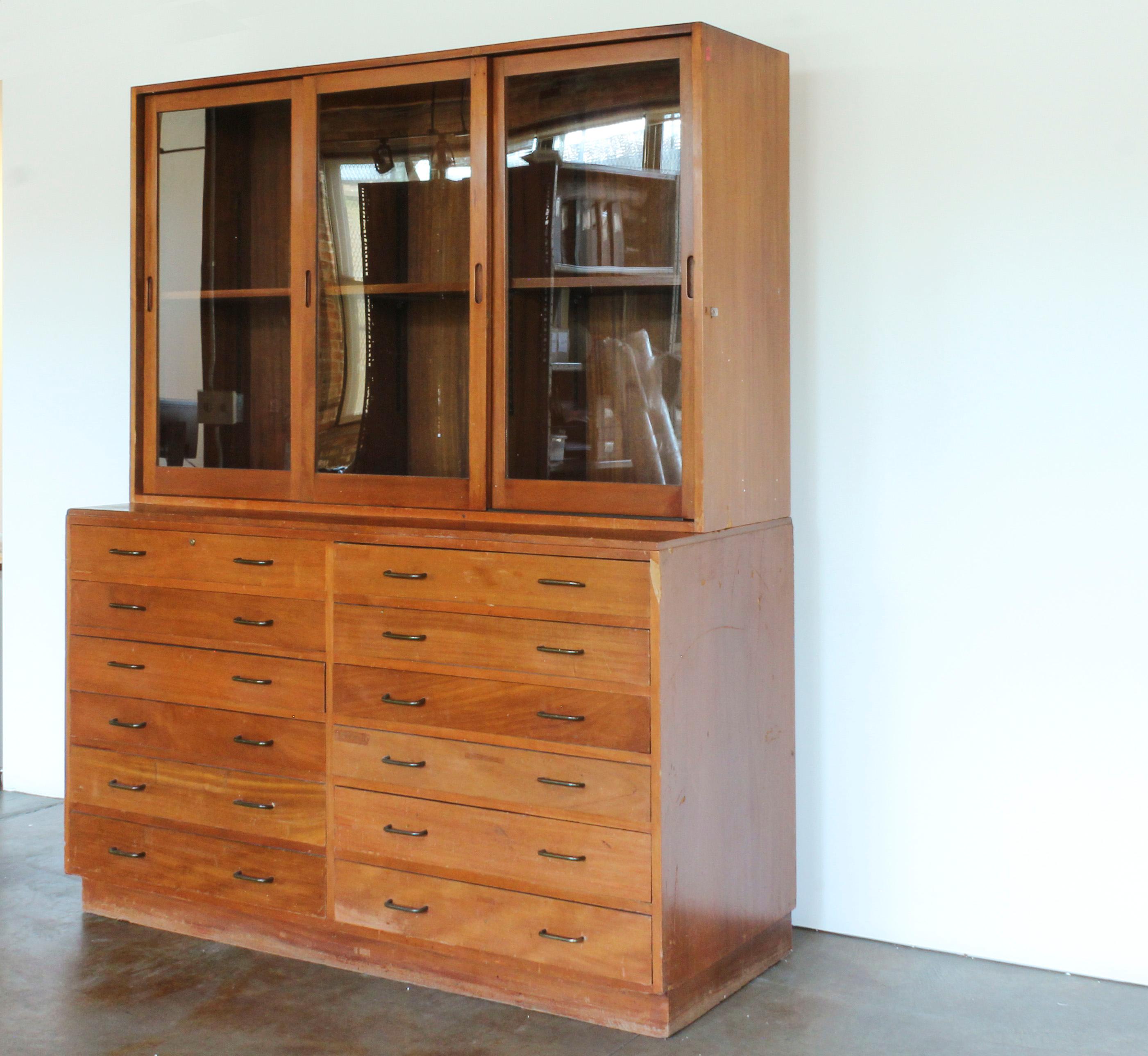 Midcentury American mahogany bookcase with 12 drawers and three glass sliding doors. Adjustable shelf in upper portion. 

Upper cabinet: 17.75