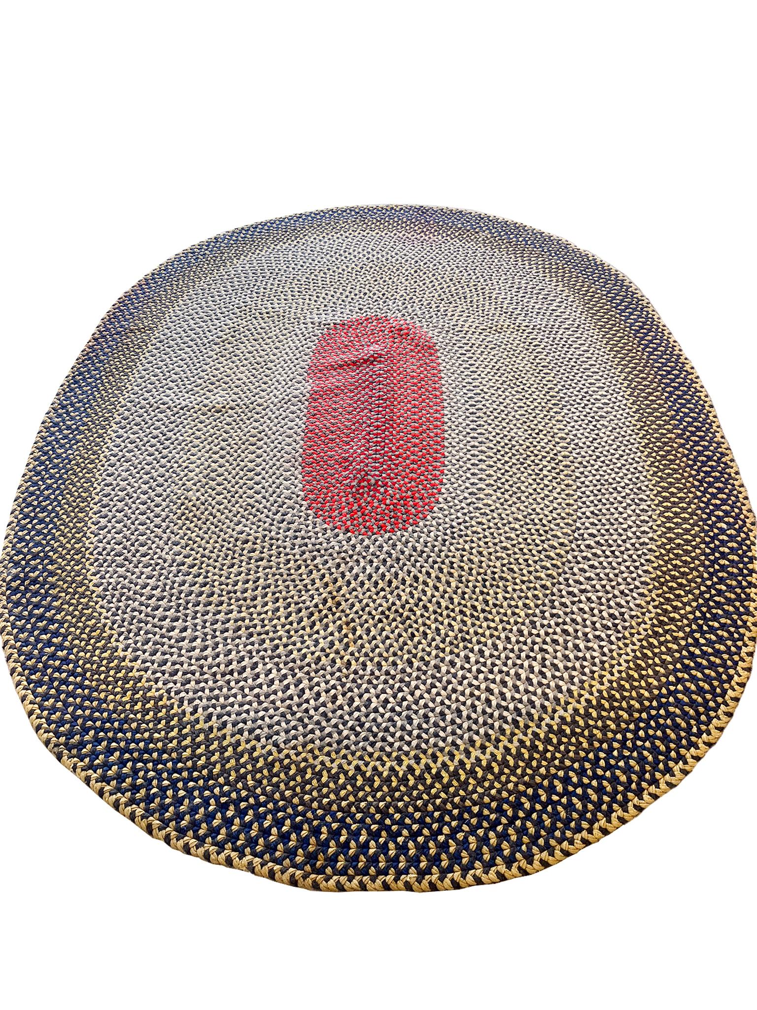 Handwoven in the 1940s, this American oval hooked rug has an eye-dazzling pattern that emerges from its intricate braided wool technique. The palette is a bold mix of yellow, blue, red, and various shades of gray. 

Dimensions:
90 in. x 111 in. (7'
