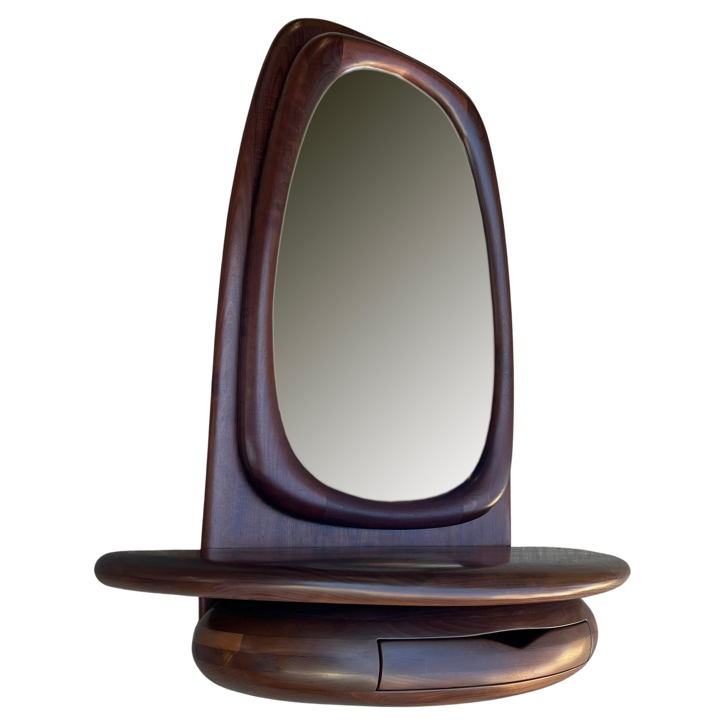 Nous vous proposons ce miroir magnifiquement sculpté par Dean Santner. Les créations du maître-artisan Dean Santner s'inscrivent dans le mouvement de l'American Modern Craft aux côtés de Wendell Castle, Nakashima, Phillip Powell et faisaient partie