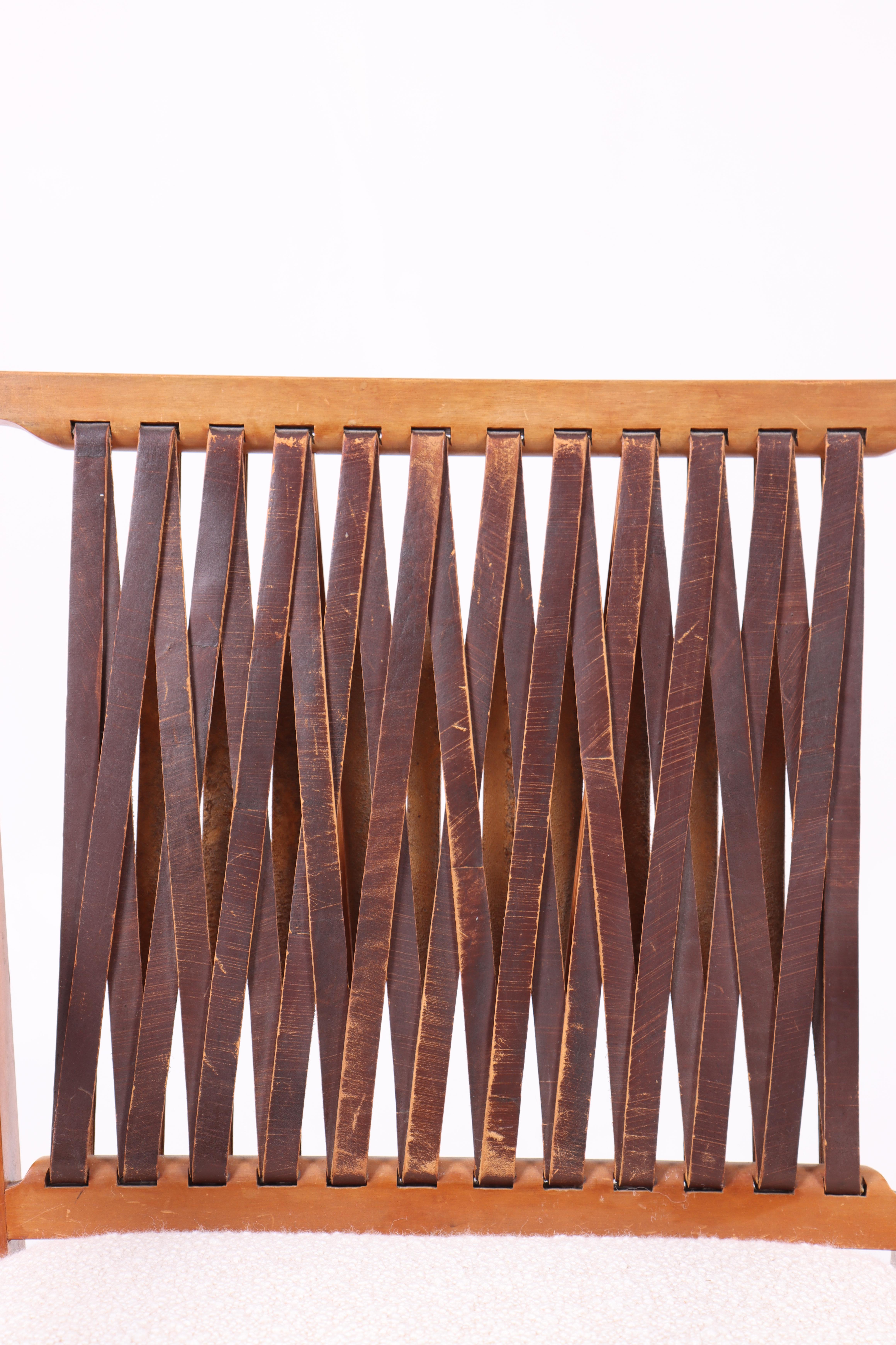 This elegant armchair is a perfect combination of classic design and modern comfort. Designed in the 1950s by a talented Danish designer, the chair features a unique leather-woven back that adds both style and durability. The seat is newly