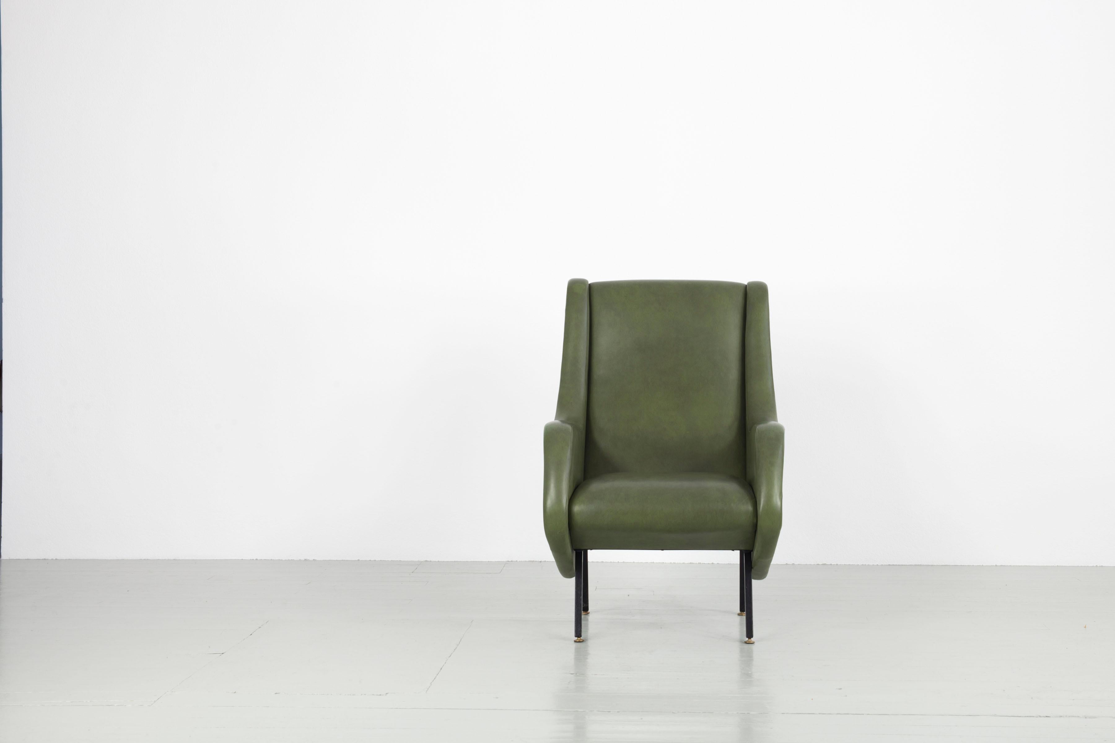Ce fauteuil dans le style d'Aldo Morbelli a été fabriqué en Italie dans les années 1950. Le fauteuil avec accoudoirs est recouvert de similicuir vert et possède des pieds en fer avec des embouts en laiton. Le meuble est dans son état