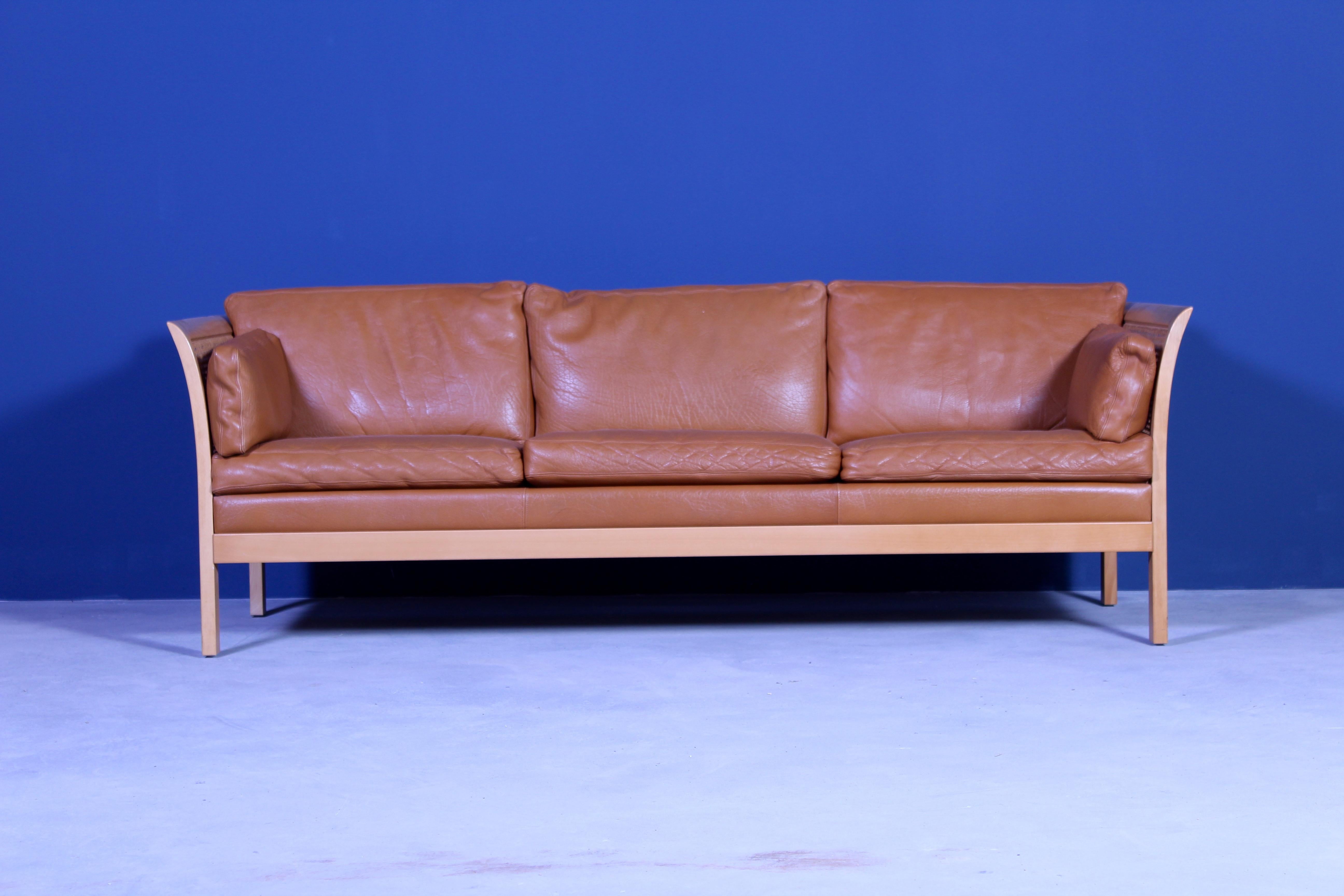 Two midcentury Swedish sofas designed by Swedish designer Arne Norell. The sofa’s has a beach frame with rattan inlays and original cognac colored leather upholstery. 2 available.

Very good vintage condition with only minor signs of usage and