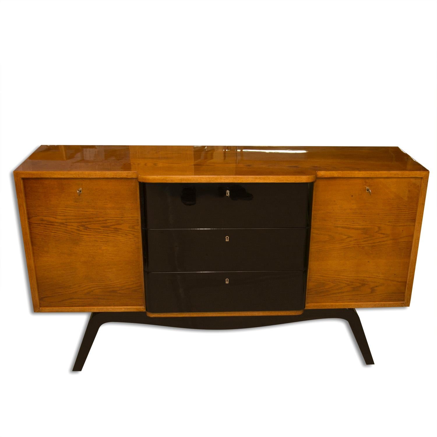 This midcentury ART DECO sideboard or chest of drawers was made in the former Czechoslovakia in the 1940´s. It is made of oakwood and the legs and drawers are varnished to a high-gloss piano finish. Very elegant and simple design. It has been fully