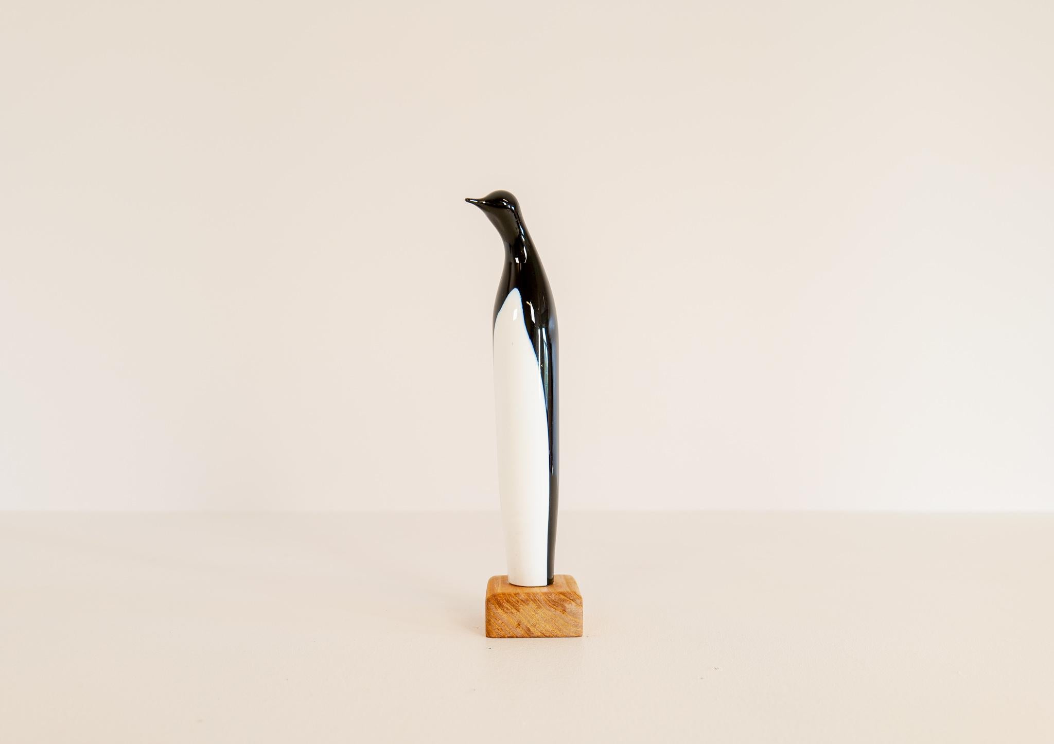 This art glass piece the penguin was produced in Sweden at the Kosta factory. Designed by Vicke Lindstrand.
The penguin is created in glass mounted on a wooden base. The line of the penguin is genially great and works perfect with the black and