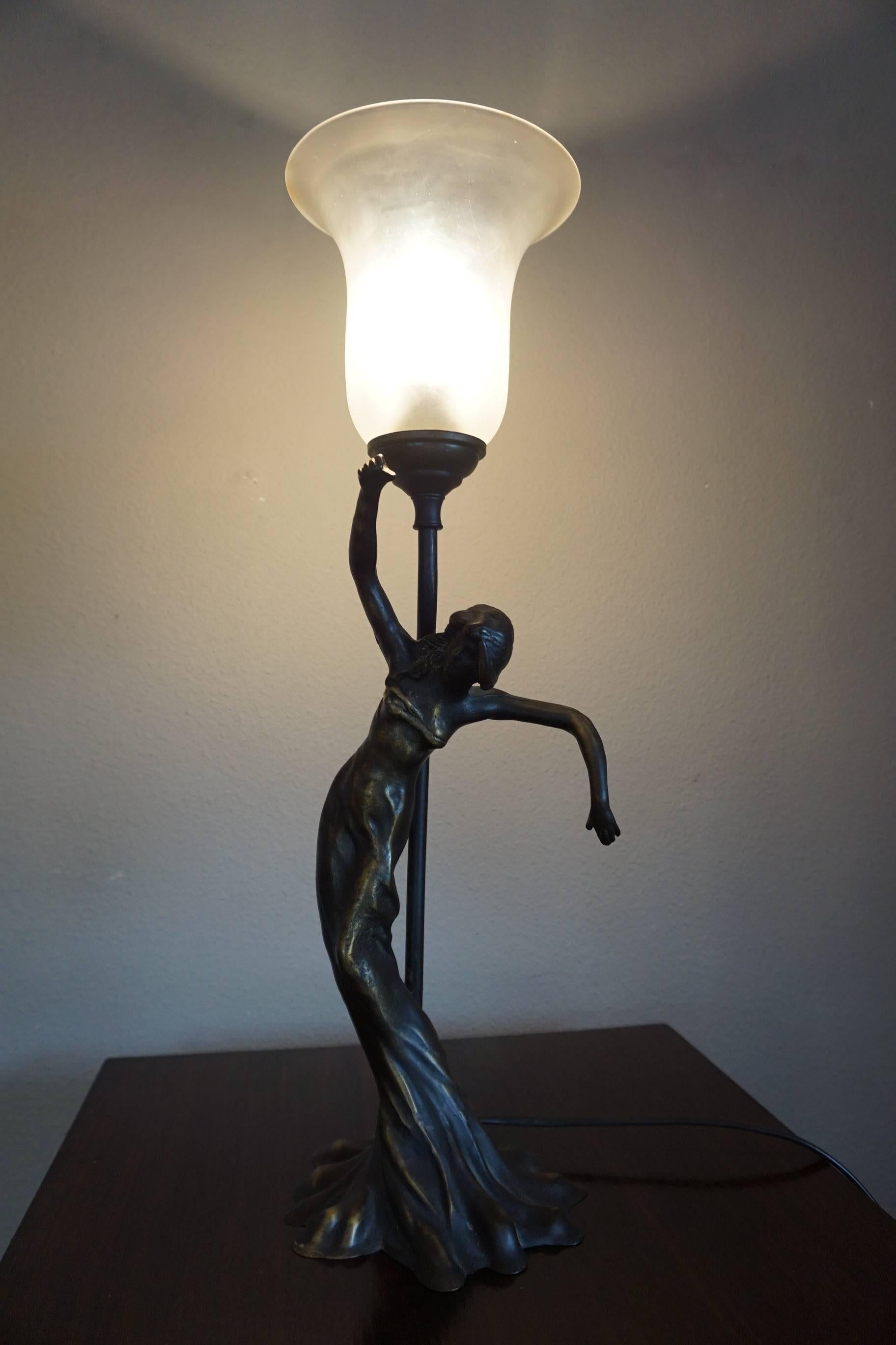 Elegant Art Nouveau style sculptural lamp with antique glass shade.

This elegantly moving and slightly sensually dressed Art Nouveau bronze lady is in excellent condition and she dates from circa 1950-1970. The satinated glass shade fits perfectly,
