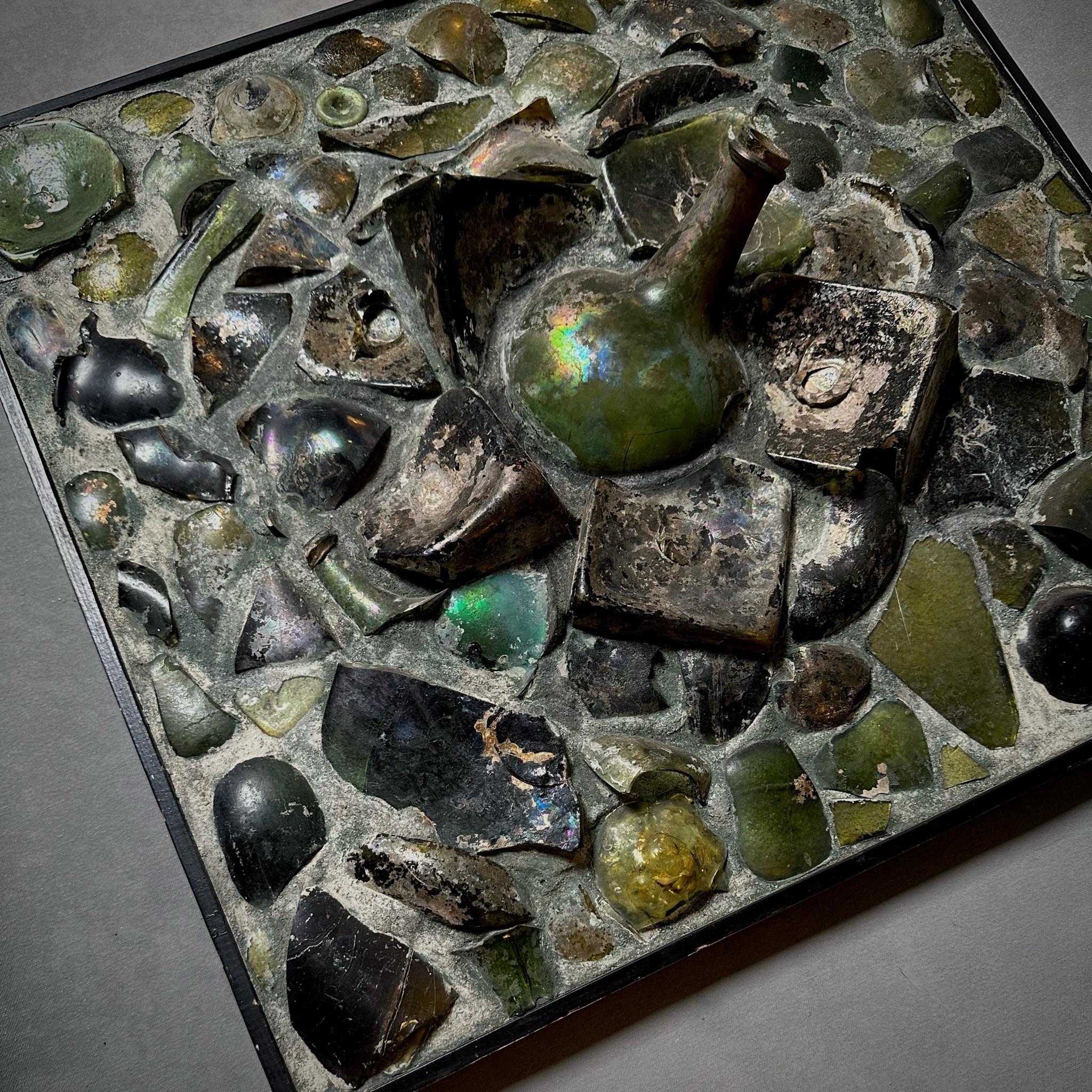 Midcentury art panel made from scraps of antique glass bottles scavenged from the infamous renovation of Amsterdam's Muntplein Square. A dynamic piece with a powerful history. 

Netherlands, circa 1940

Dimensions: 22.5W x 1.5D x 21.5H.