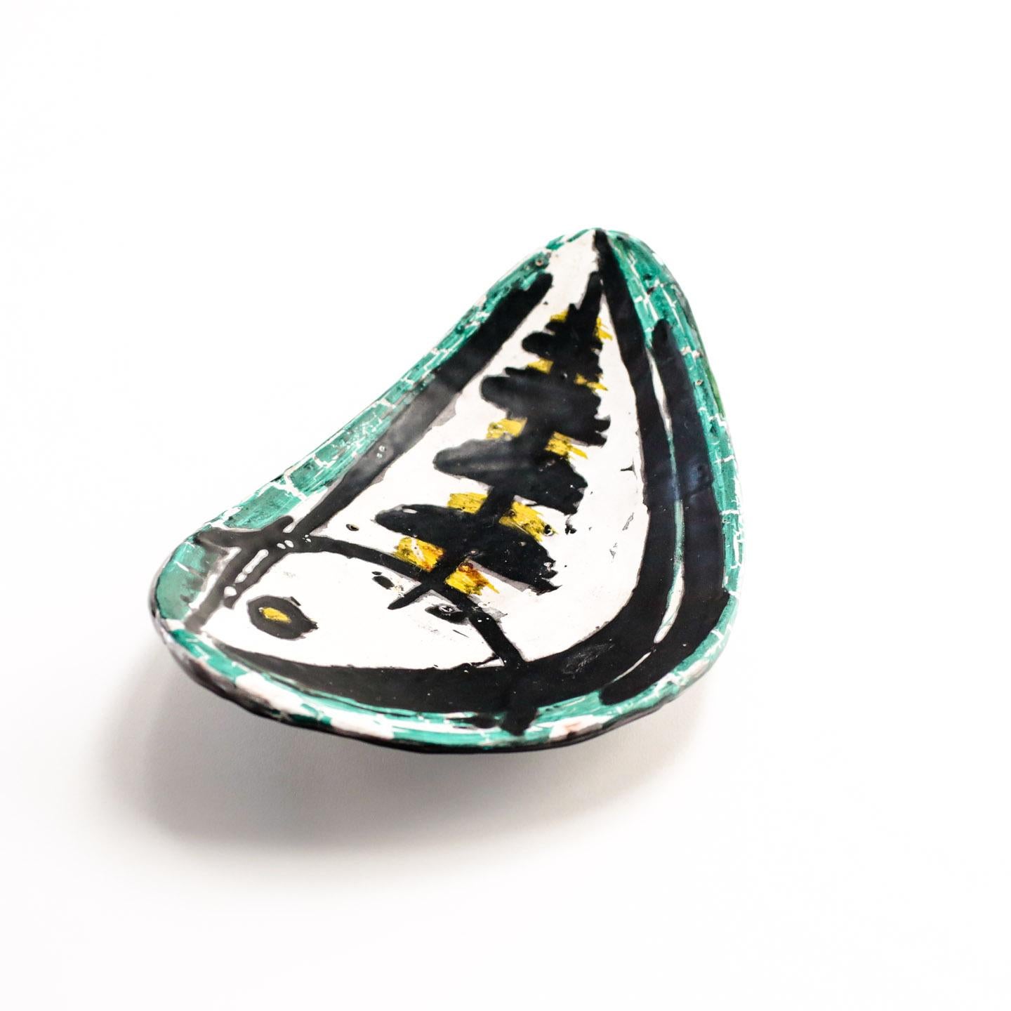 A midcentury art pottery footed dish or plate, hand-painted and glazed with a stylized fish design, signed Livia Gorka, Hungary, circa 1955.