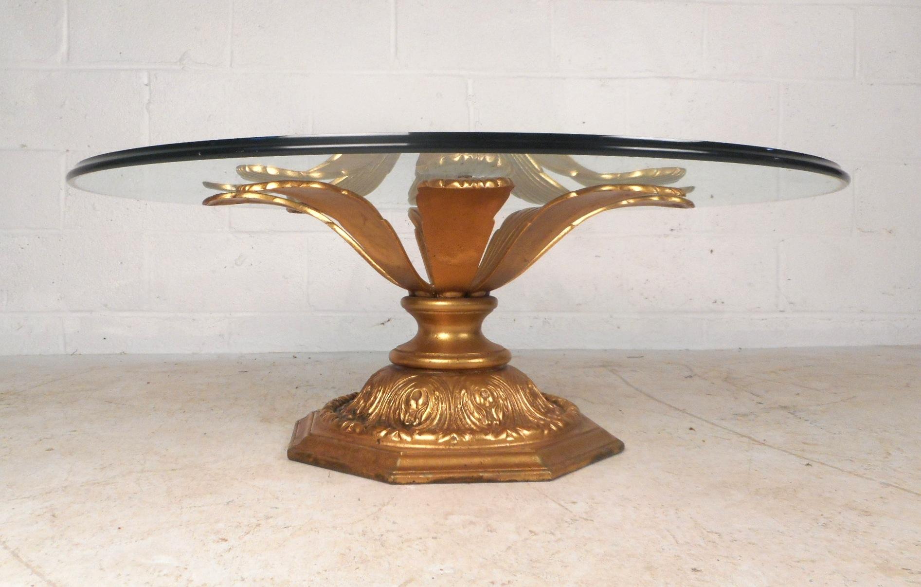 This stunning vintage Hollywood Regency style coffee table features a gilded metal base shaped like a blossoming flower. Wonderful design with a decorative octagonal base with interesting detail etched throughout. This impressive cocktail table