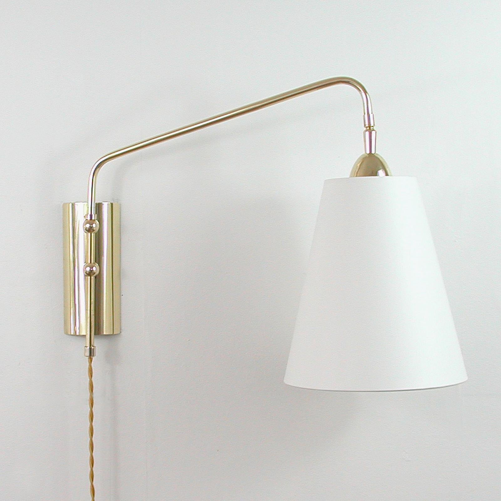 This Mid-Century Modern swing arm wall light was designed and manufactured in Austria in the 1960s. It features a brass back plate and an articulating lamp arm. The handmade lamp shade is off-white silk and is new. The direction of the shade is