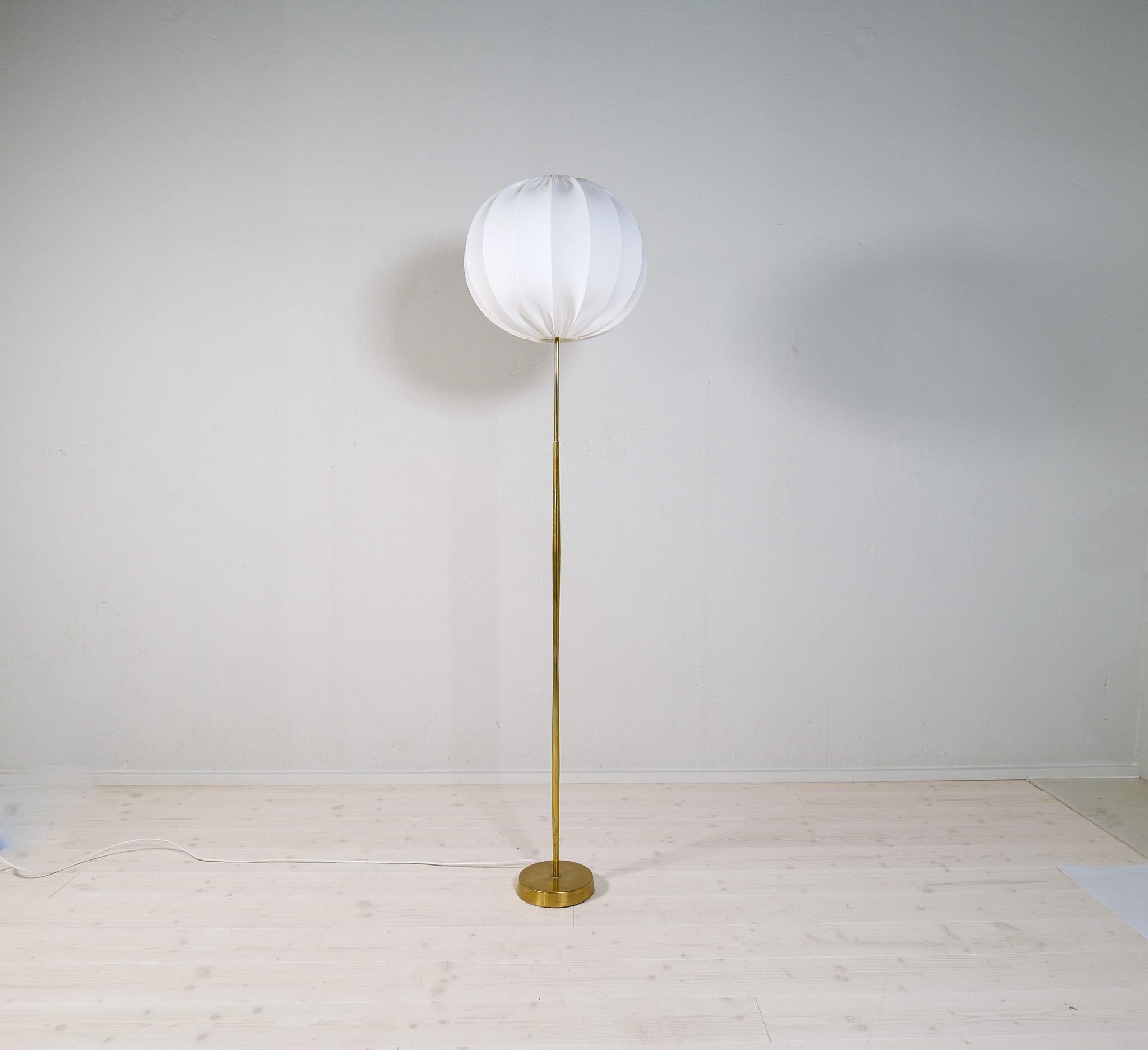 A gorgeous floor lamp made in brass with time glass shaped rod. Produced for ASEA this wonderful lamp was most likely designed by Hans Bergström.

Good working condition with spots and signs of use on the base. All new cotton shade produced in