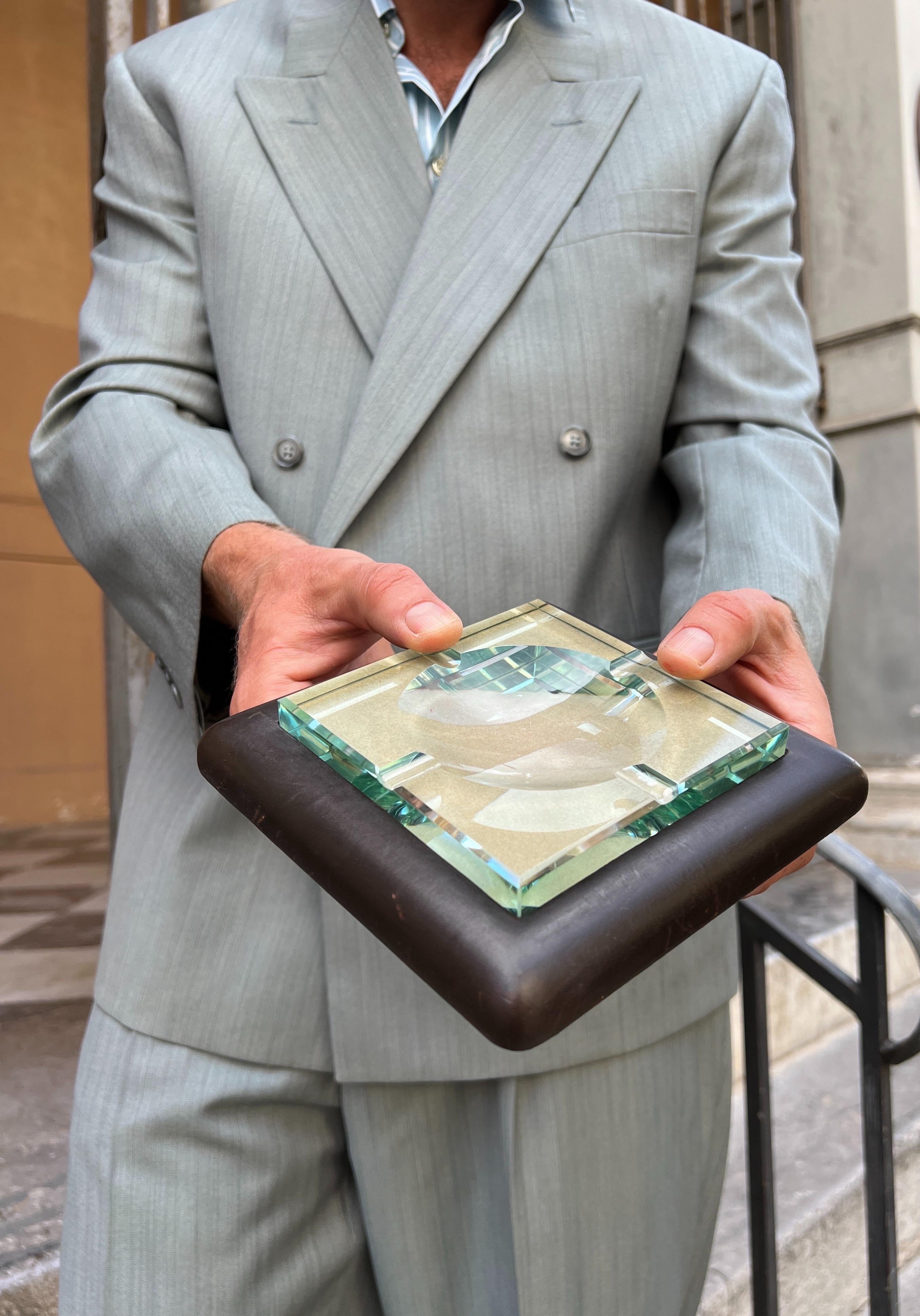 Indulge in the elegance of this exquisite ashtray, crafted in Italy during the prestigious Fontana Arte's prime in the 1960s. The square-shaped design boasts a transparent crystal glass with a subtle green hue, exquisitely placed on a dark brown