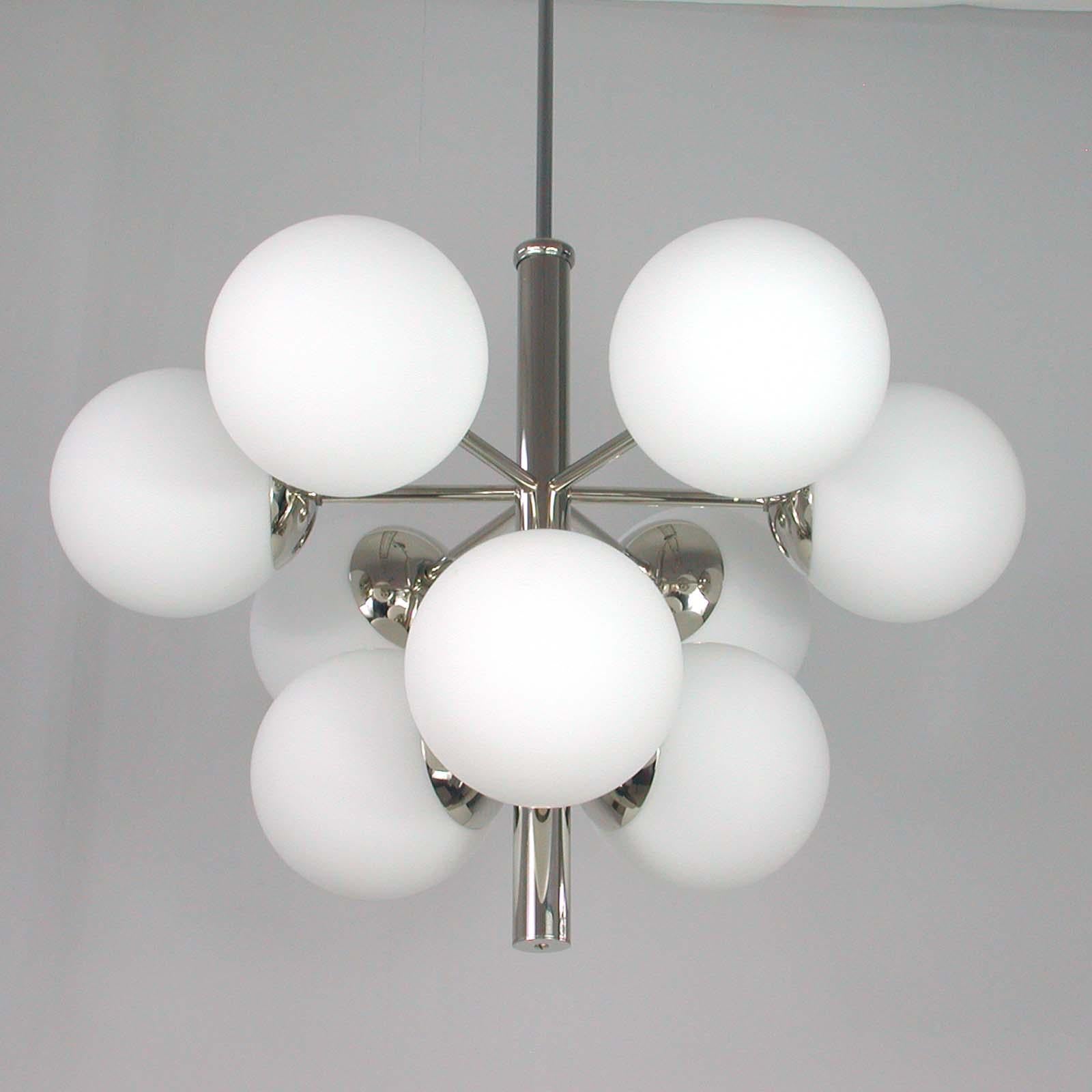 This beautiful chandelier was designed and manufactured in Germany in the 1960s by Fischer Leuchten. It is made of chrome-plated metal and has got nine white frosted satinated glass lamp shades. Each lamp shade has got an E14 screw on socket.