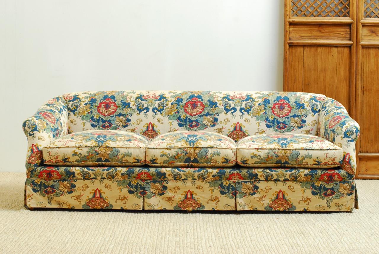 Stunning Mid-Century Modern English chinoiserie style sofa by Baker Furniture. Features a vibrant chinoiserie fabric with flowers and dragons. The frame has English style rolled arms and back. The seat has deep fitted cushions and pillows with