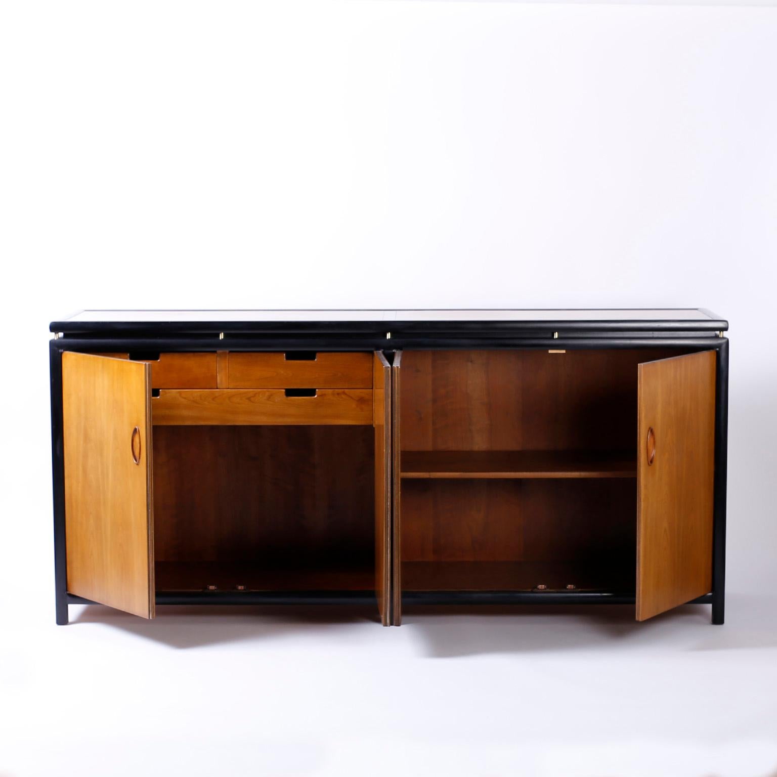 Sleek modern four door cabinet with an ebonized frame and walnut top, sides and front, Featuring chic inset handles and plenty of storage with signed Baker in a drawer.
