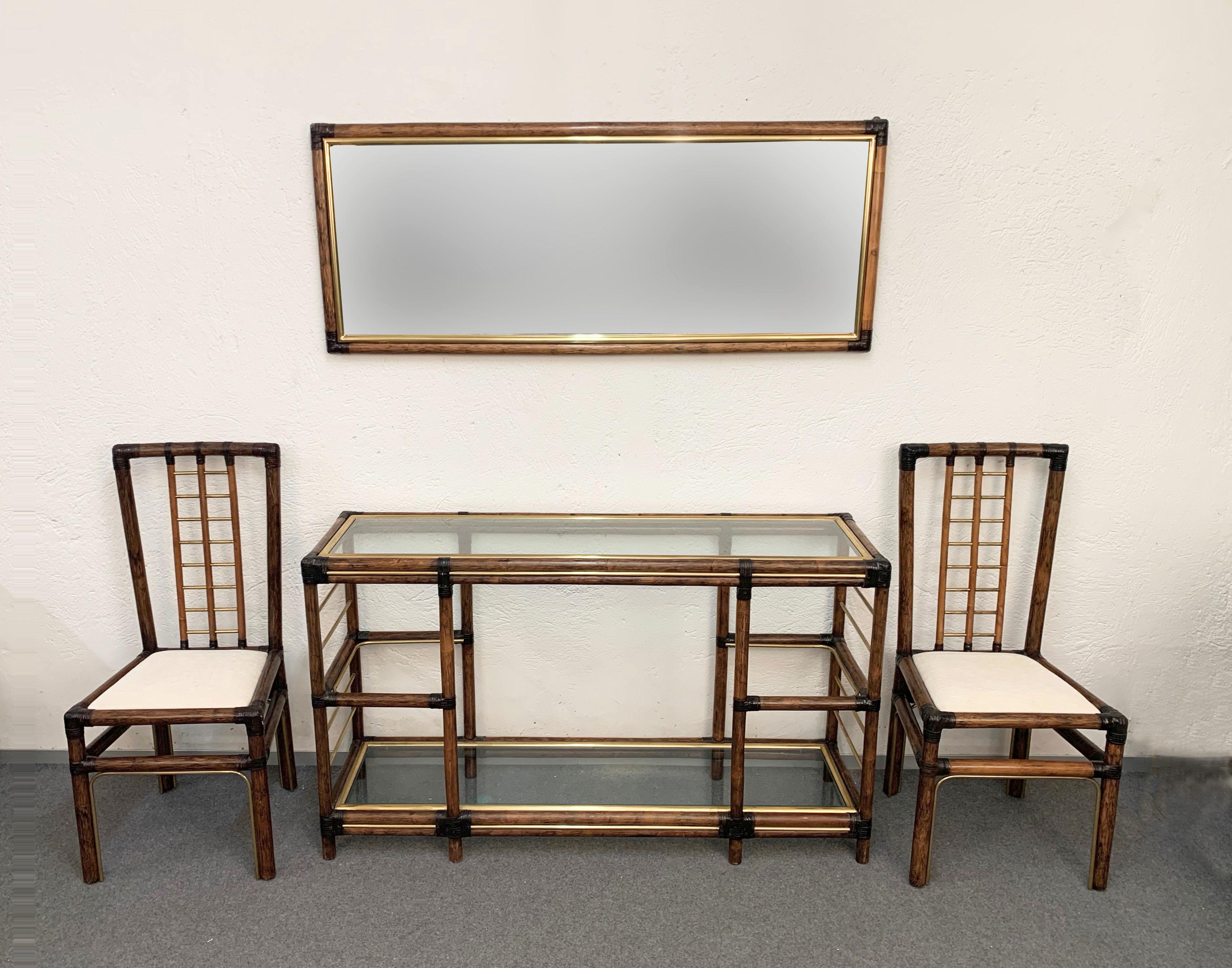 Wonderful bamboo and brass midcentury entrance hall set. This incredible set was produced in Italy during the 1980s.

This amazing set is made of a console table with crystal glass shelves, a wall mirror and a pair of chairs with white fabric